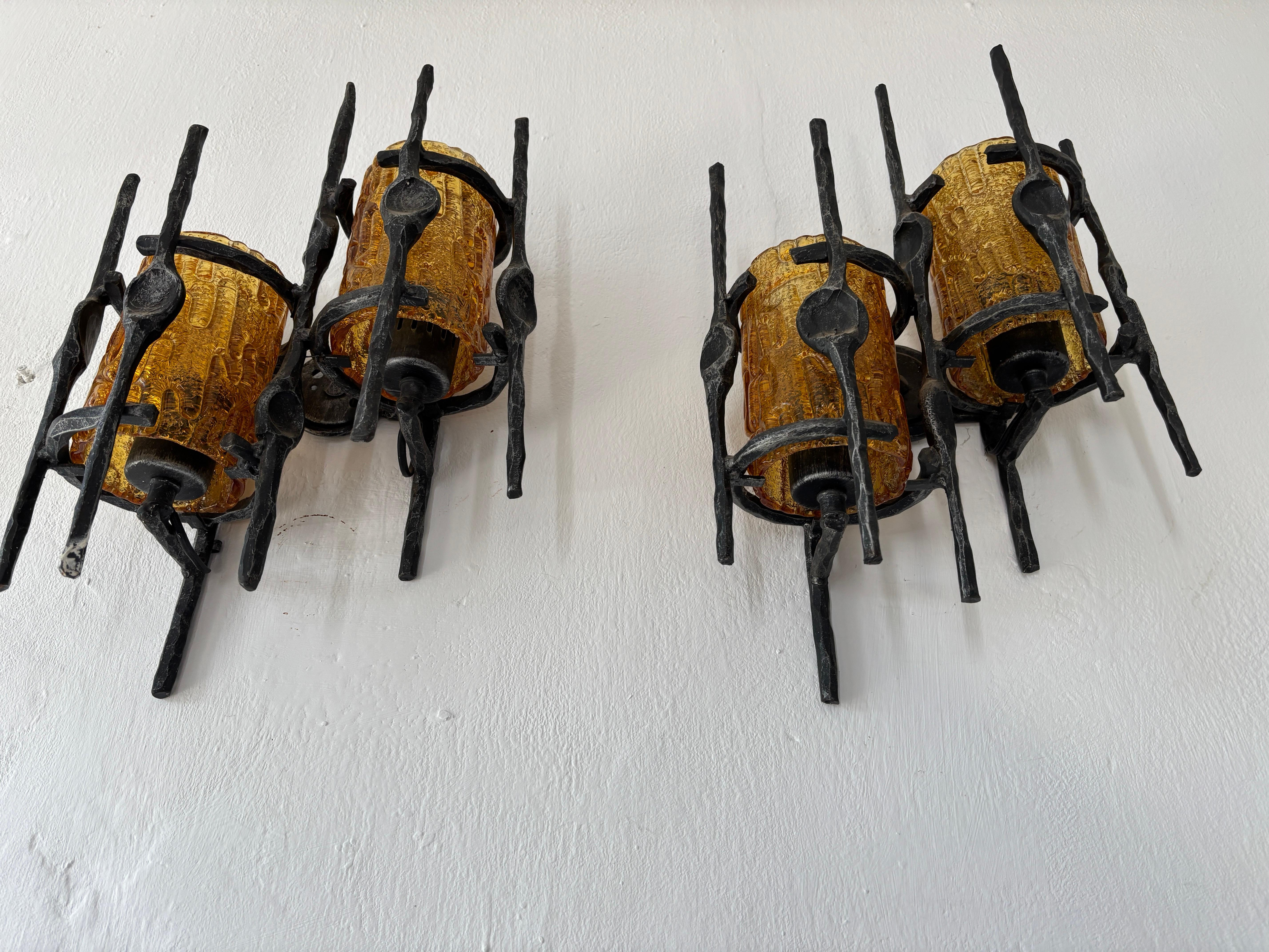 Pair of brutalist sconces with thick amber Murano glass covering bulbs.  Will be rewired with certified UL US socket for the USA and an appropriate socket for all other countries and ready to hang. Wrought iron body with amberMurano glass. Free