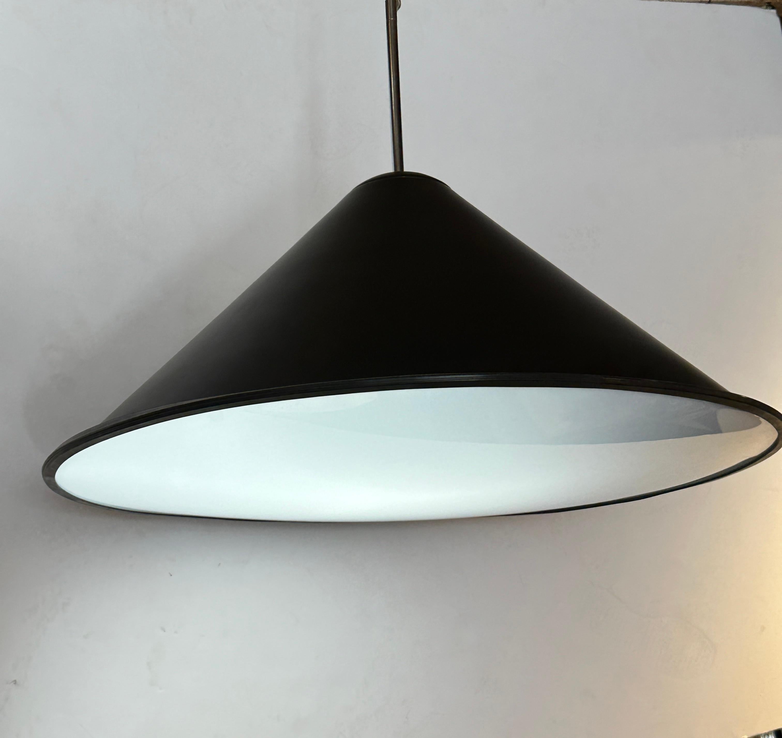 The Tom Dixon large pendant light features a deep, lustrous black lacquer shade and a frosted plexiglass screen which filters the light and creates a warm inviting atmosphere. The pendant light is crafted with exceptional attention to detail,