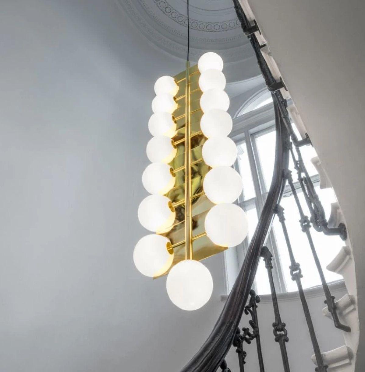 Tom Dixon plane brass drop chandelier, 4-layer, white glass, geometric mod light. A brass-plated statement drop chandelier comprising of 4 double-layered white glass spheres distributed seven rotating planes. This space-filling chandelier creates a