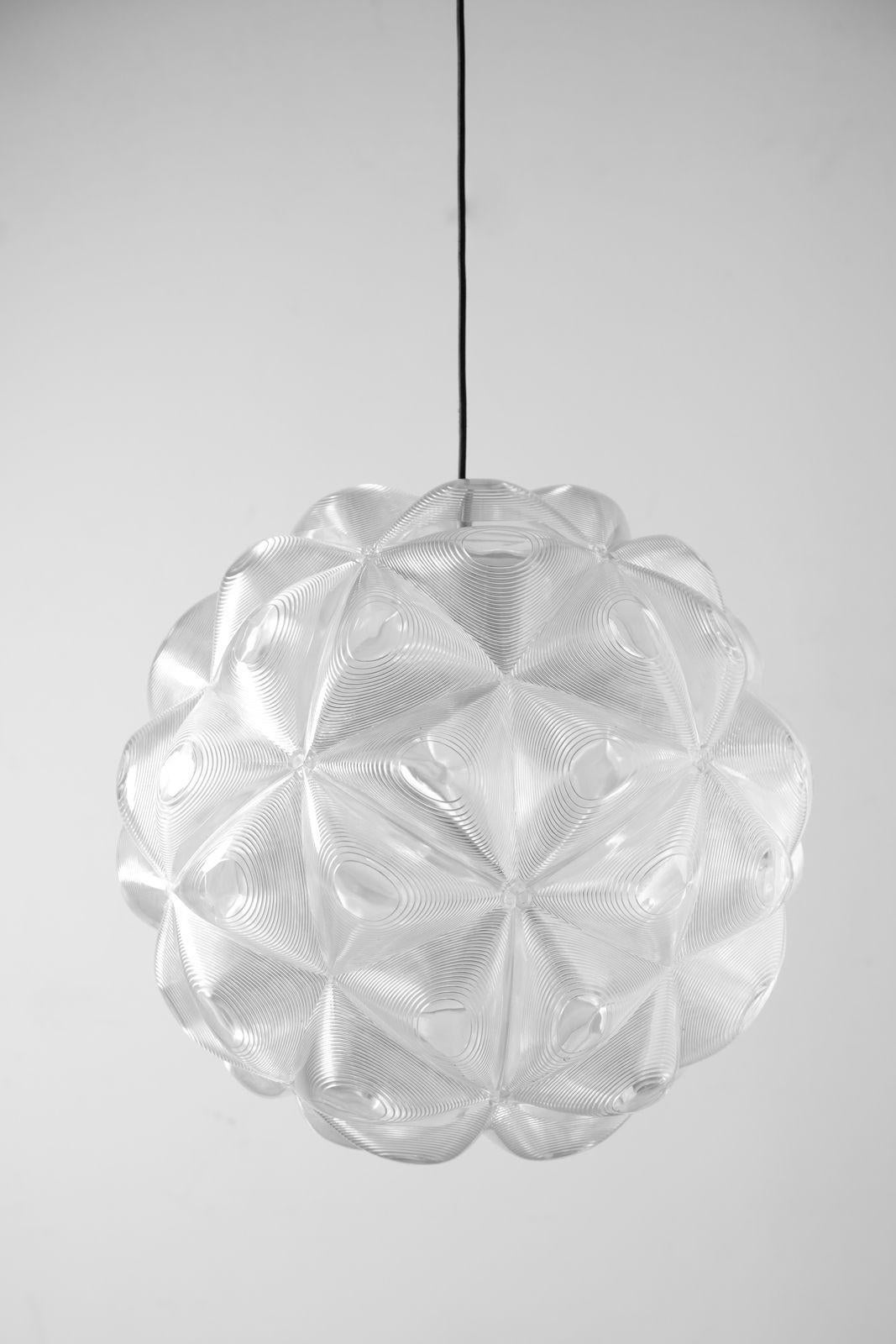 The Lens pendant is an extraordinary contemporary suspension lamp by Tom Dixon. It's made from 60 individual triangular polycarbonate lenses that surround the interior light source. The clear lenses refract and focus the lightbulb at various angles