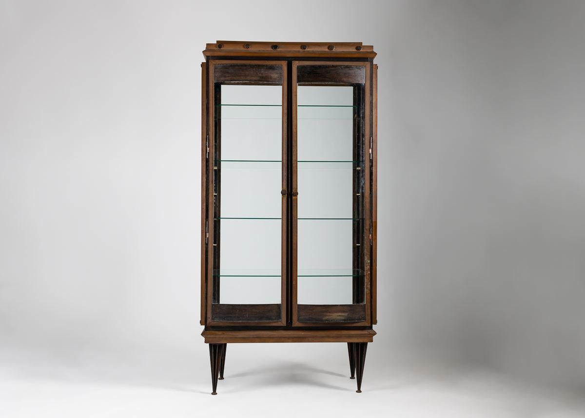 This elegant two-door cabinet by renowned British designer Tom Dixon combines heft with light. Its sturdy bronze frame rests on tapered legs while the glass sides and shelves lend to the objects it displays a sense of weightlessness. 