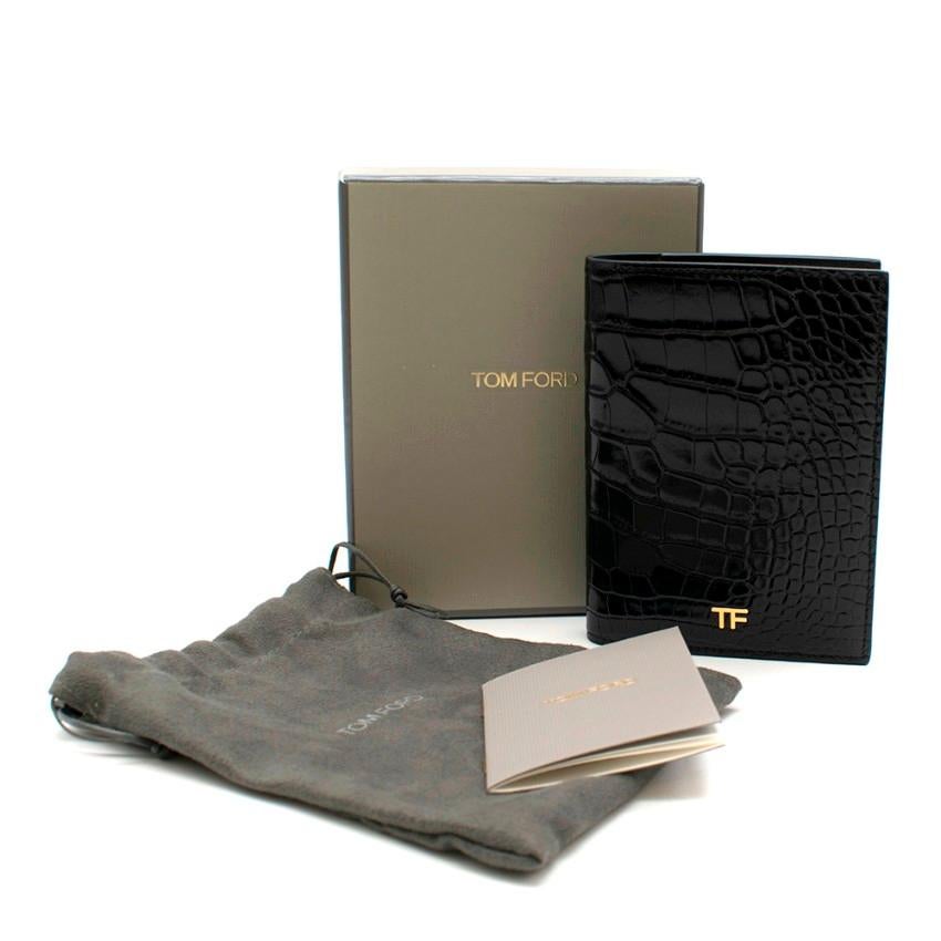 Tom Ford Black Shiny Alligator Passport Holder 

- 6 credit card slots
- Cash slots
- Smooth leather lining
- Brand new in box
- Gold tone TF Logo
- 10 X 13.5 X 1 CM
-  Made in Italy

Please note, these items are pre-owned and may show some signs of