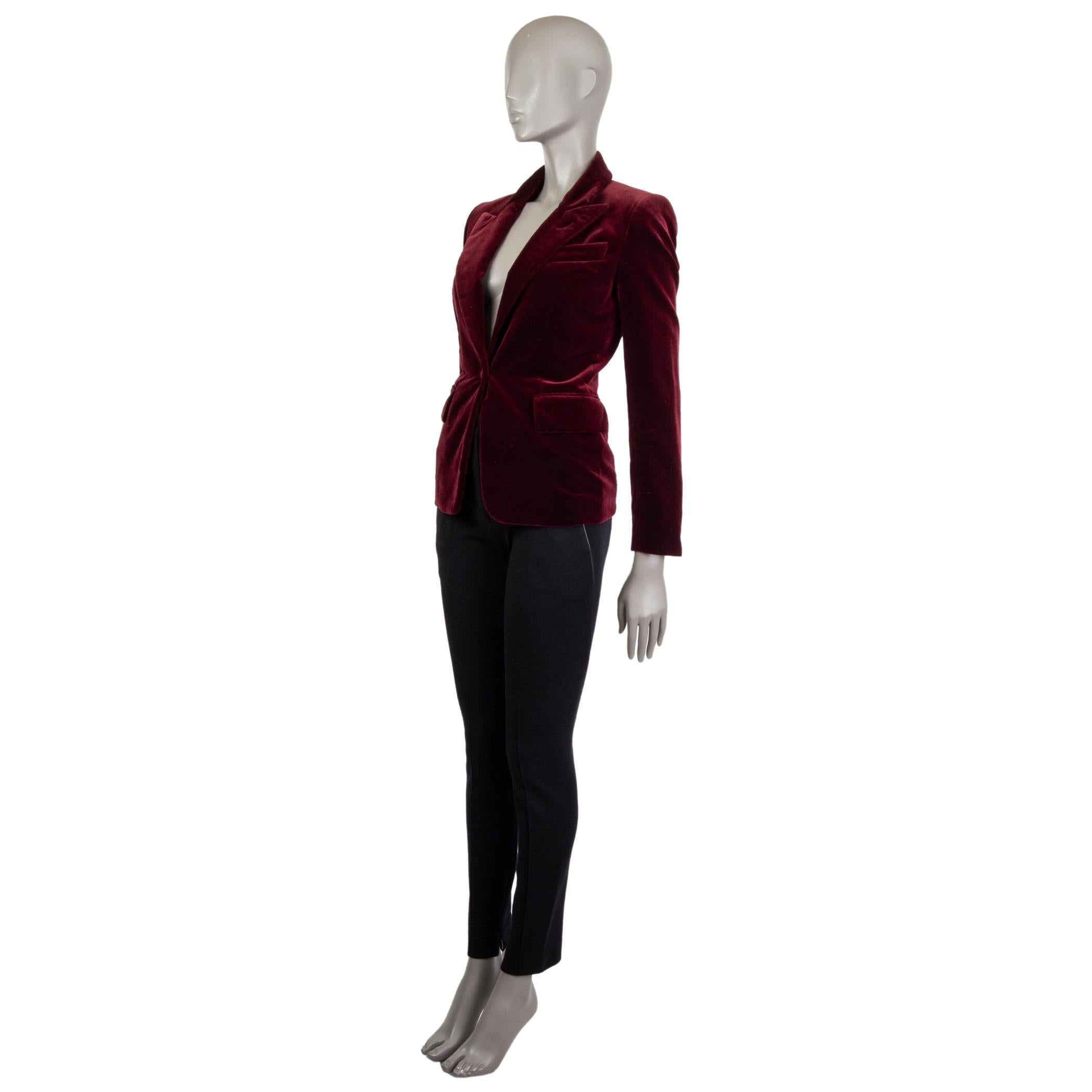 Tom Ford velvet blazer in burgundy cotton (100%). With peak collar, chest pocket, two flap pockets on the sides, and buttoned sleeves. Closes with one button on the front in matching velvet. Lined in deep red satin silk (100%). Has been worn and is