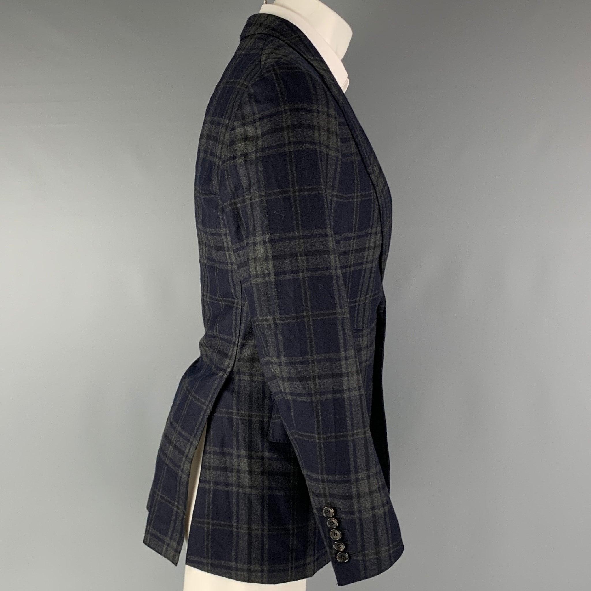 TOM FORD sport coat comes in a navy and grey plaid wool and cashmere woven material with a full liner featuring a peak lapel, flap pockets, double back vent, and a double button closure. Excellent Pre-Owned Condition. 

Marked:   46 R