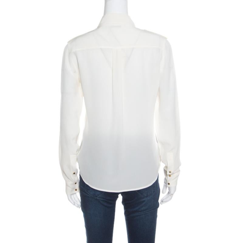 Chic and very modern, this cream blouse from Tom Ford deserves all your attention! It is made of 100% silk and styled with sharp collars, twin chest pockets and epaulettes that are detailed with gold-tone screw shaped buttons. It comes with long