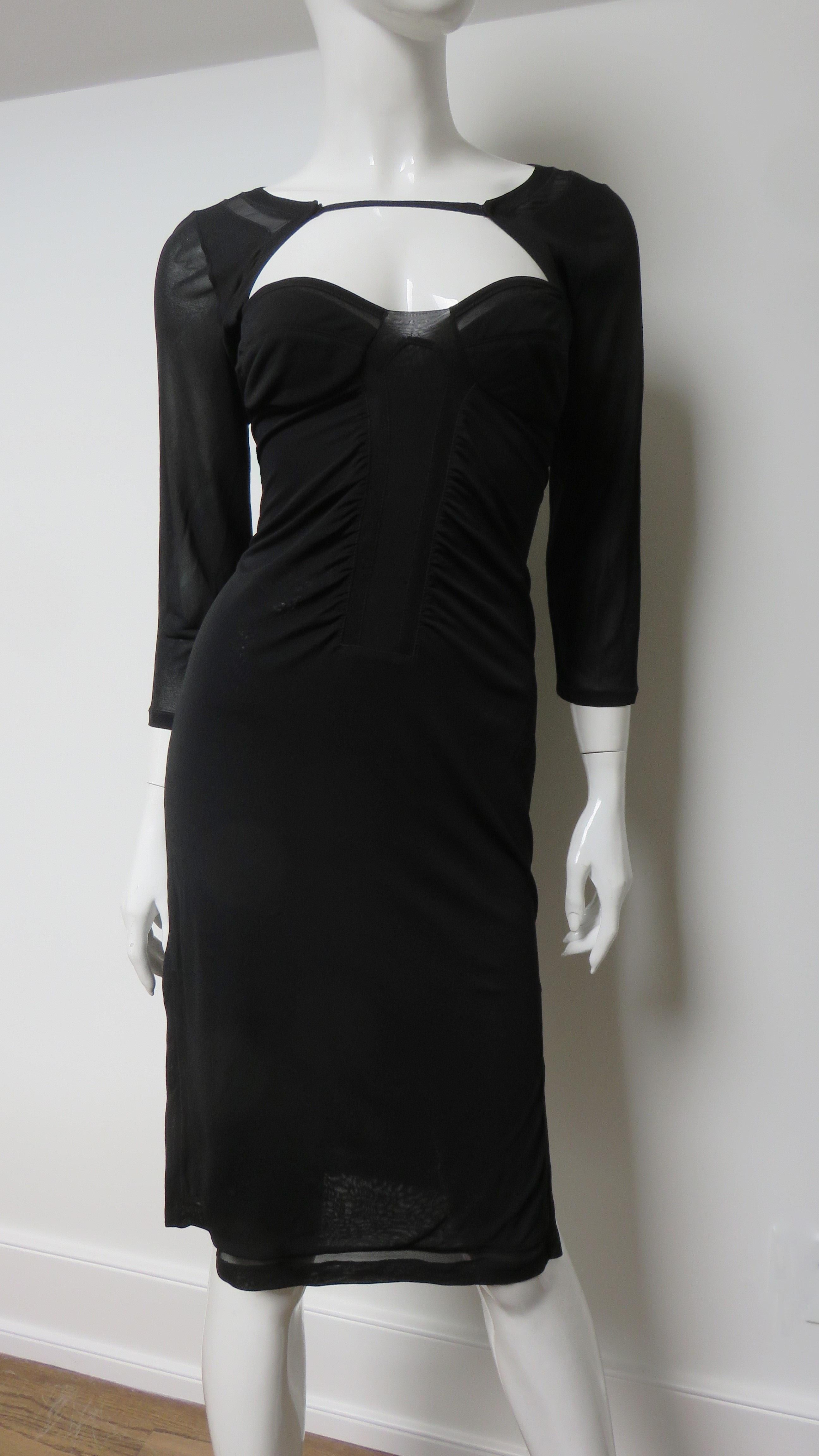 A fabulous black fine stretch silk dress from Tom Ford for Gucci. It has 3/4 length sleeves, slits at the side hem and a fine strap crossing the upper chest and back. There is a ribbon sized sheer panel around the hem and bust. It slips on over the