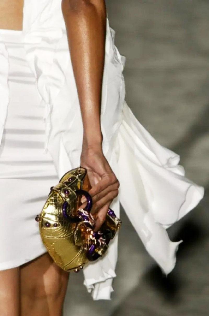 Highly collectible Gucci Limited Edition Clutch Bag designed by Tom Ford back to 2004.
This luxurious, stand-out clutch features a gold snake skin, Swarovski-encrusted crystals and enamel double serpent head horsebit design at its front. Purple