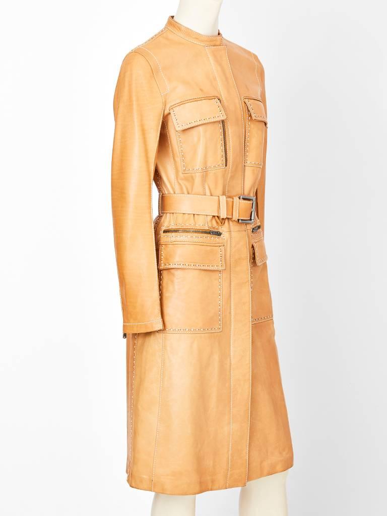 Tom Ford for Yves Saint Laurent, natural tone, leather belted coat, having flap pockets at the breasts and hips. These pockets are key features having zipper embellishments.
Coat has a rounded collar and hidden zipper closure with white top