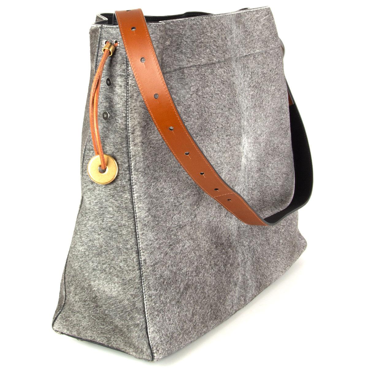 Tom Ford large hobo bag in grey calf hair with black and camel calfskin adjustable shoulder strap with gunmetal fisherman hook detail. Opens with a brown drawstring and is lined in black microfibre with one leather zip pocket and one open pocket.