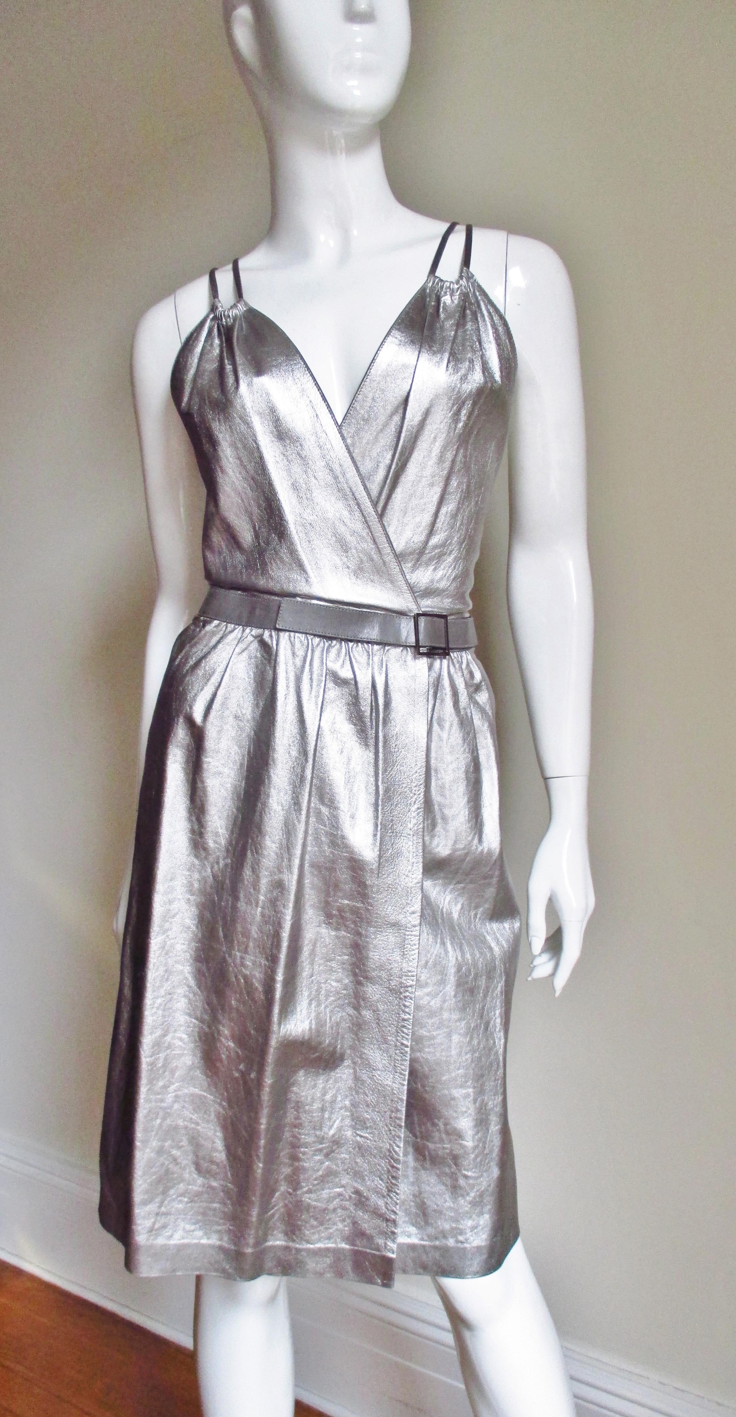 Un precioso vestido envolvente de piel plateada de Tom Ford for Gucci . El corpiño se cruza por delante envolviendo la cintura y cerrándose con botones a presión.  Tiene un fino cinturón de cuero gris a juego con los tirantes que se extienden por