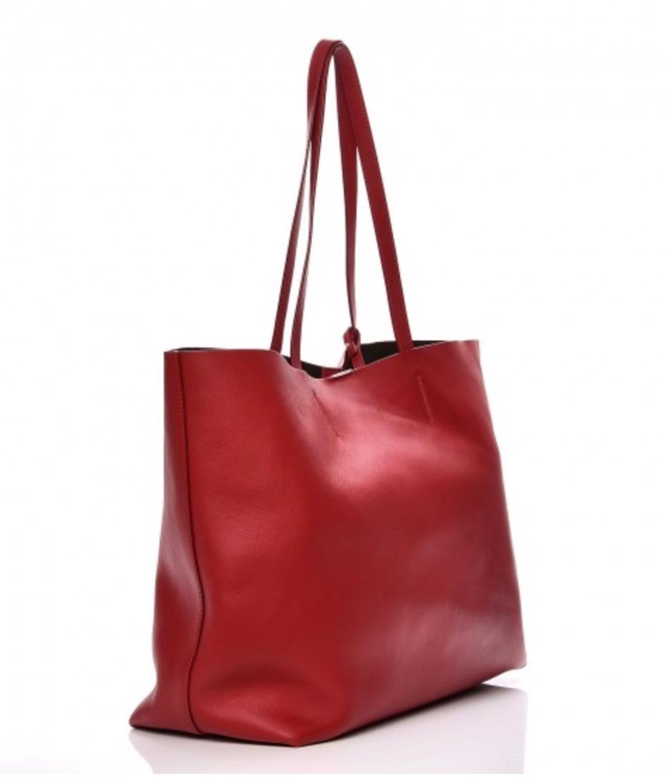 This Tom Ford Tote shoulder bag is made with smooth calfskin leather in red. The bag features a perforated TF on the front, an open top with snap closure and a brown microsuede interior. Includes a hanging zipper companion pouch attached to the