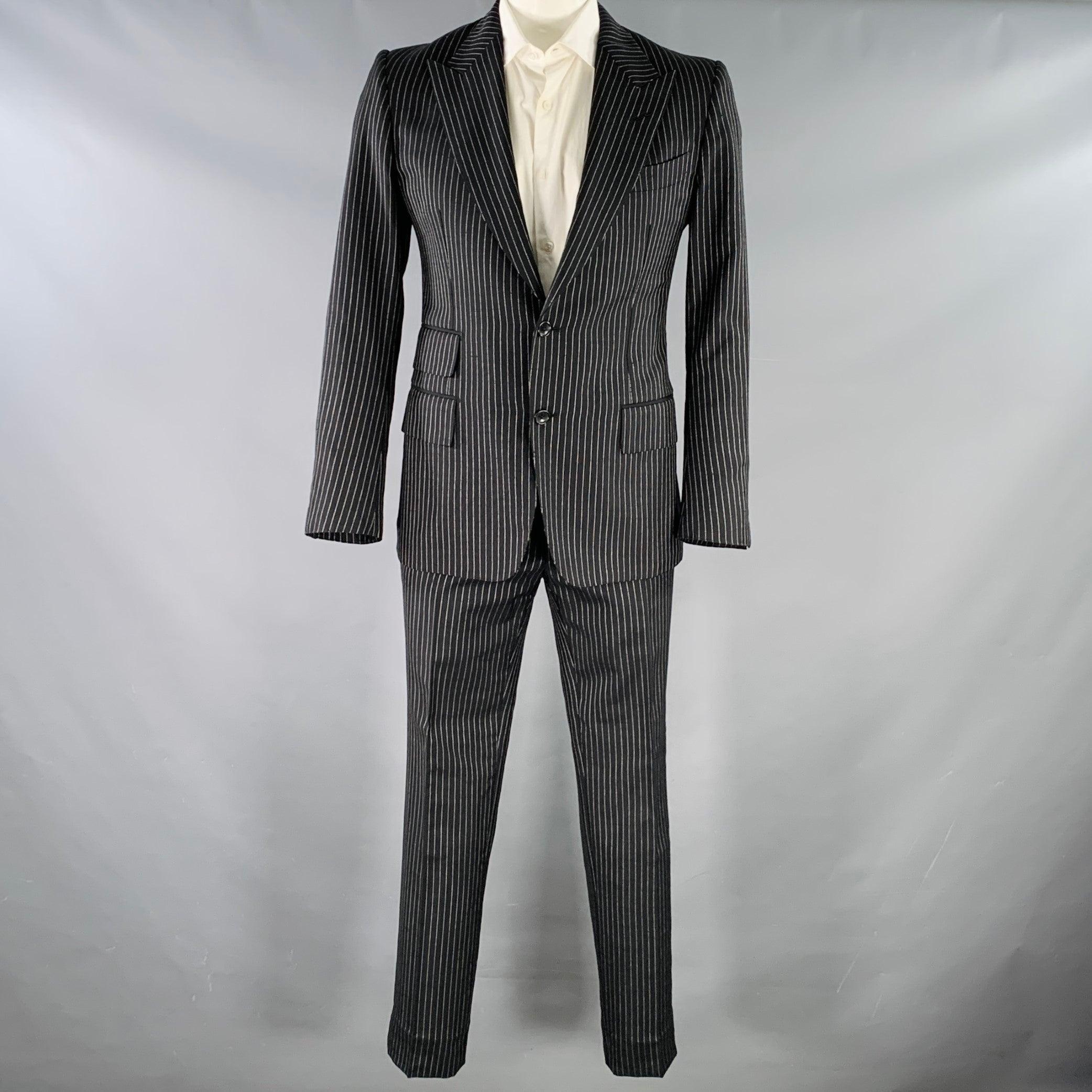 TOM FORD suit
in a black and white pinstripe virgin wool mohair with a full liner and includes a single breasted, double button sport coat with a peak lapel and matching flat front trousers.Very Good Pre-Owned Condition. Minor signs of wear.