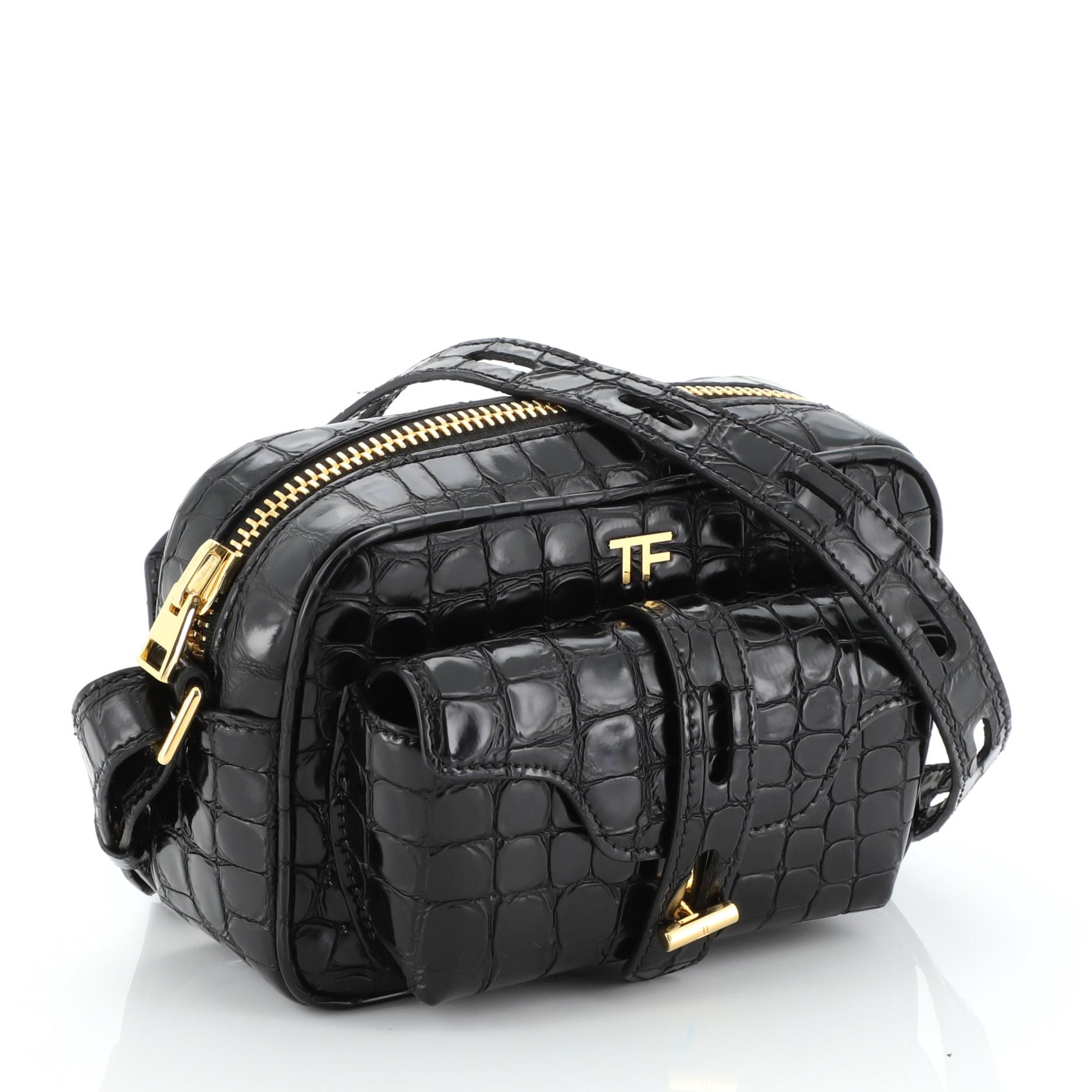 This Tom Ford T Twist Camera Bag Crocodile Embossed Leather, crafted from black leather, features exterior front pocket, front logo, leather strap and gold tone hardware. Its closure opens to a black leather interior. 

Estimated Retail Price: