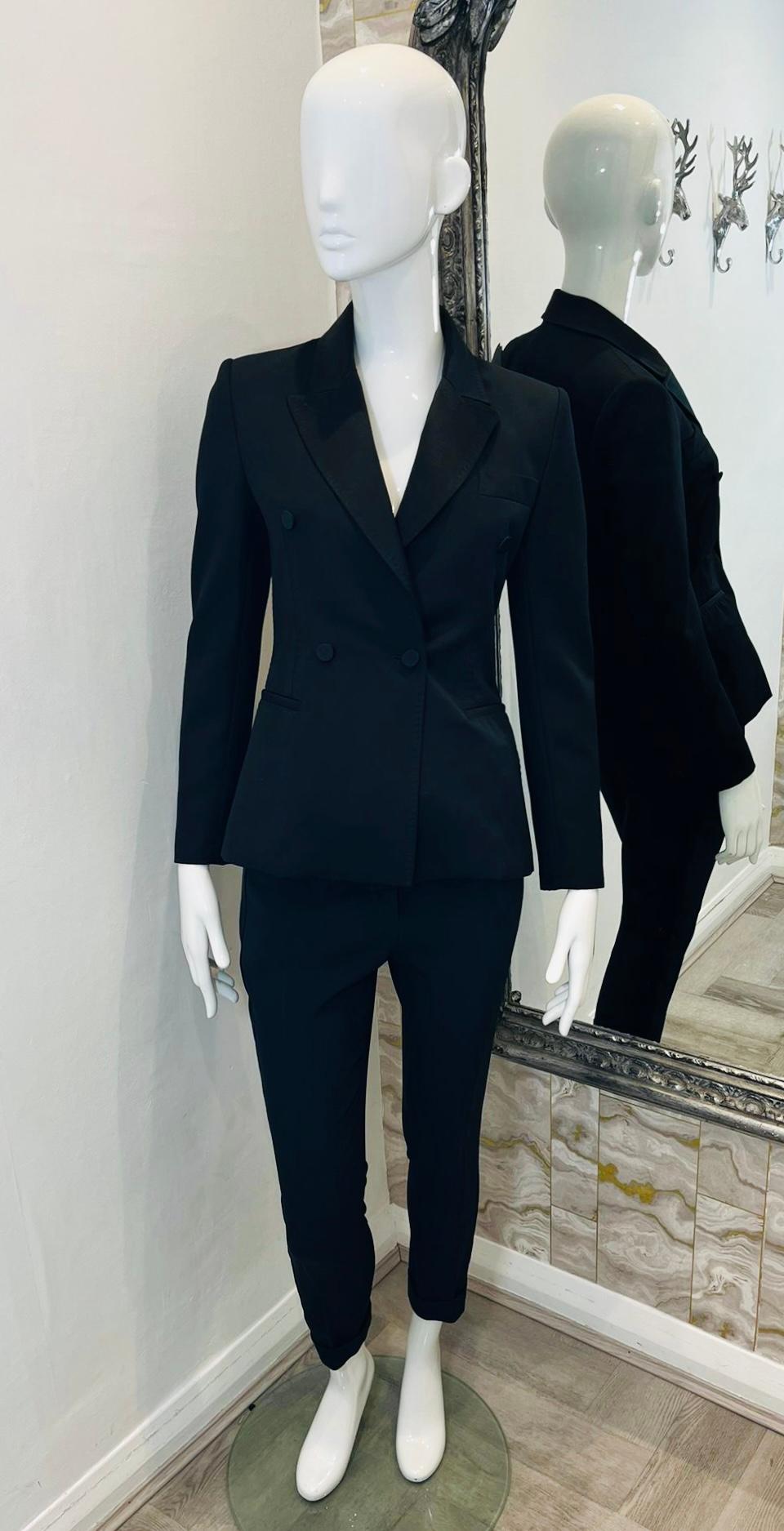 Tom Ford Tailored Two-Piece Suit

Black suit consisting of double-breasted jacket and slim fit trousers.

Fitted blazer designed with satin notched lapels, buttoned cuffs and three welt pockets.

Slightly cropped trousers detailed with satin strap