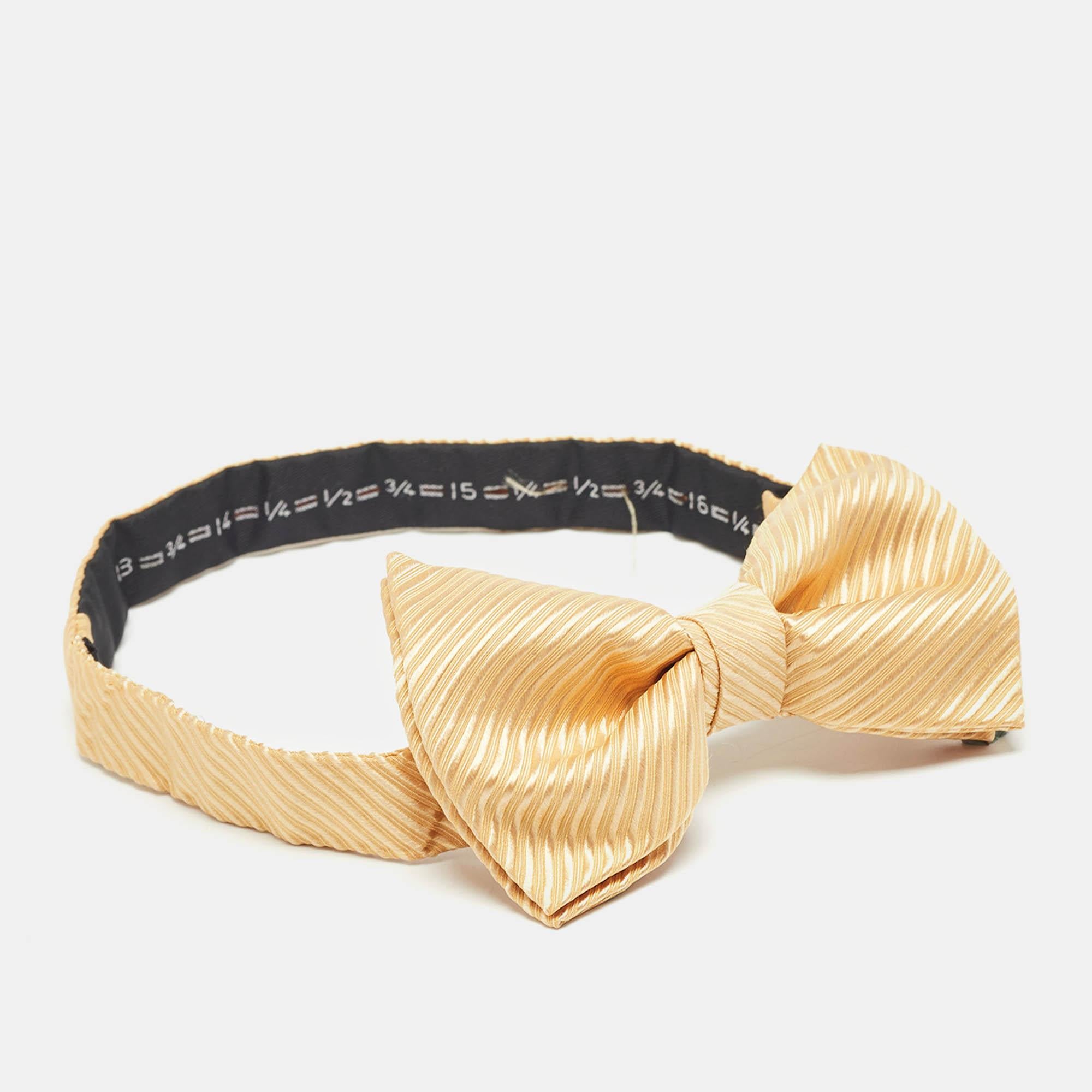 The Tom Ford bow tie showcases a vibrant yellow hue with subtle stripes offering a perfect blend of luxury and style. Crafted from premium silk it adds a touch of refinement to any formal attire making it an ideal accessory for discerning gentlemen.