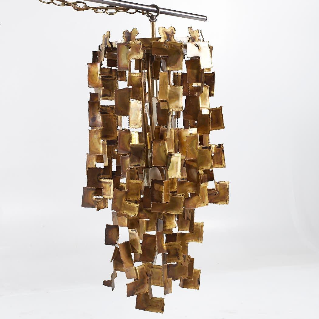 Tom Green Mid Century Brutalist Brass Chandelier 

This chandelier measures: 14 wide x 14 deep x 31 inches high

We take our photos in a controlled lighting studio to show as much detail as possible. We do not photoshop out blemishes. 

We keep you