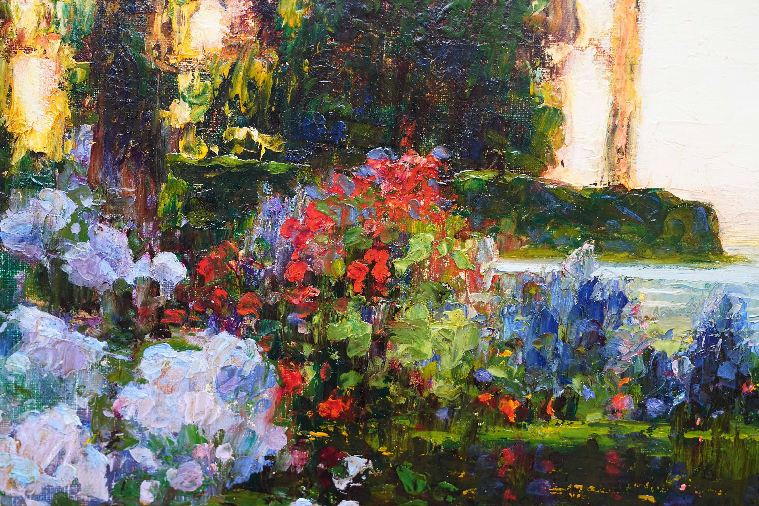 This lovely British Edwardian Impressionist oil painting is by noted artist Tom Mostyn. Painted circa 1910, the composition is a view looking out over a pond with fountain, across grass towards the sea. The whole painting is bathed in soft evening
