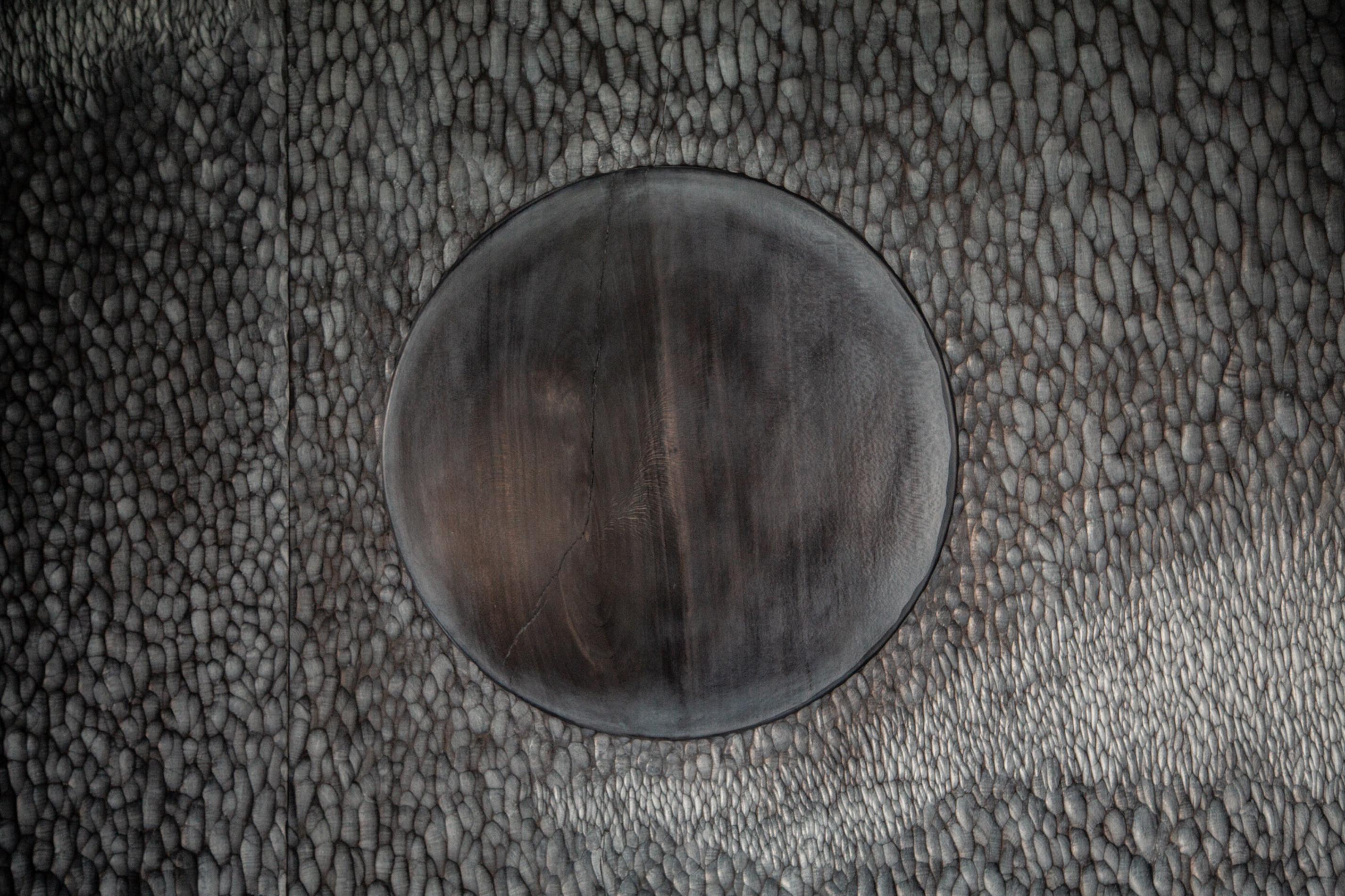 An intricately carved wall mounted screen representing the full moon and clouds reflecting on a pool of rippling water.  This piece has a Japanese aesthetic, both striking and calming in atmosphere it is entirely hand-carved in three panels of