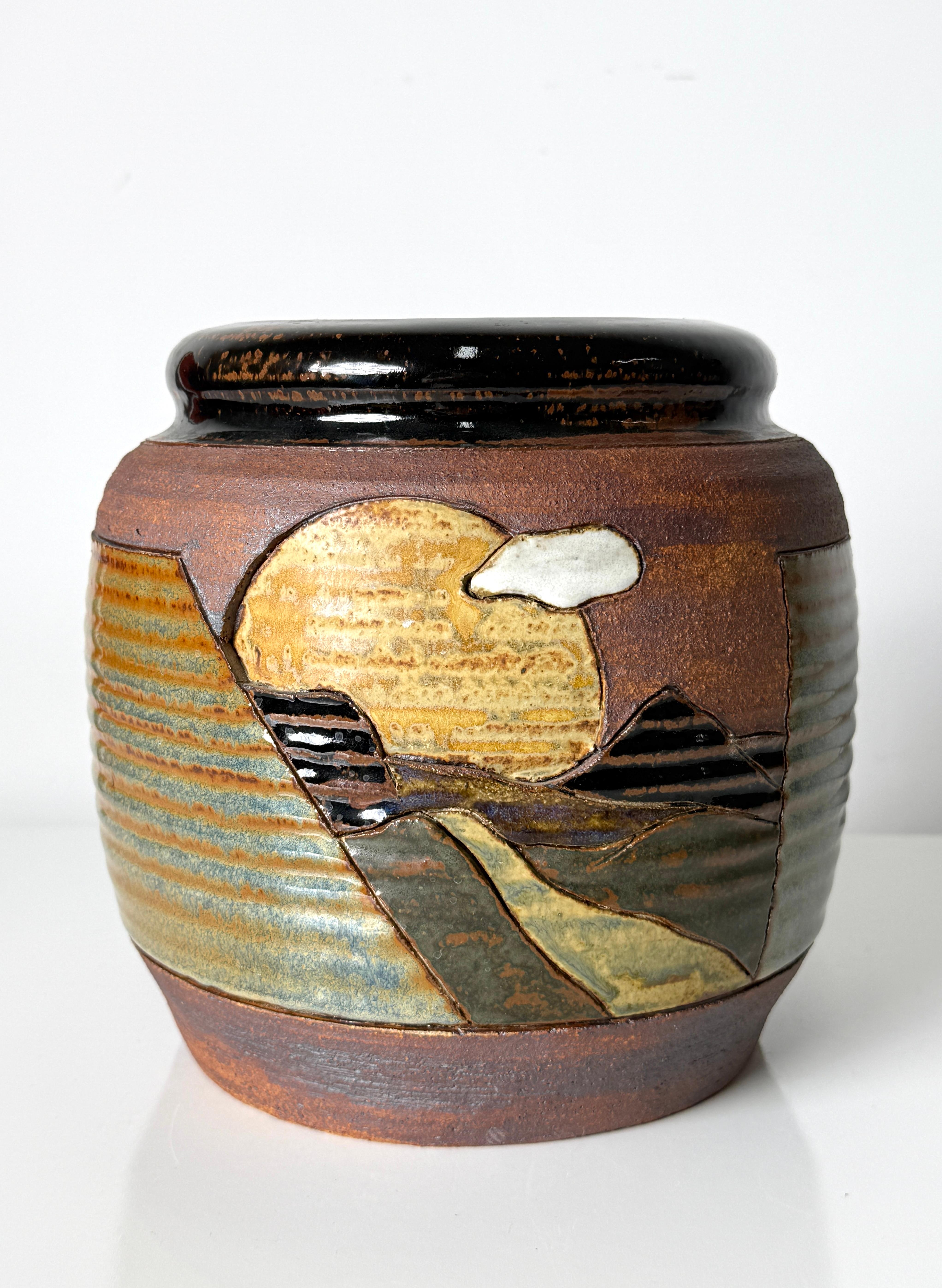 Stylized decorative landscape vase by Detroit ceramic artist Tom Phardel circa 1980s

Glazed stoneware vessel with carved color block landscape design in a warm natural color palette
Signed to underside

9.5 inch diameter
9 inch height