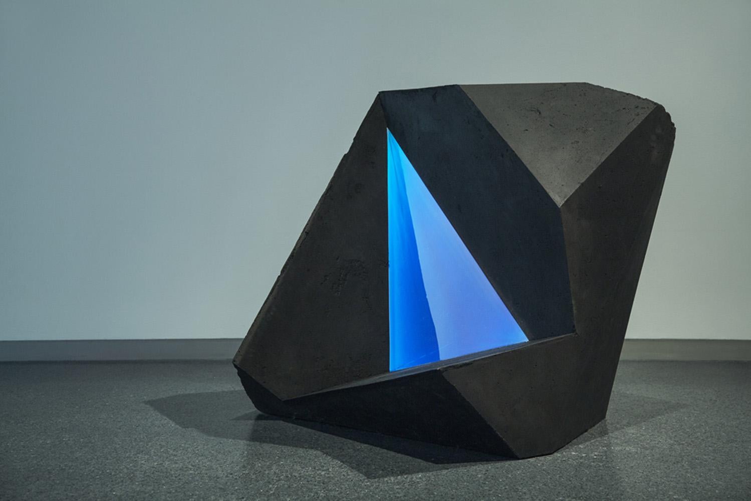 Coal, polyester resin, Jesmonite. 100 cm × 100 cm × 100 cm.
The artist created the Carbon Voids series by combining various geometric ‘positive’ (creating solids) and ‘negative’ (creating voids) shapes. In Carbon Void Blue, a resin triangle is