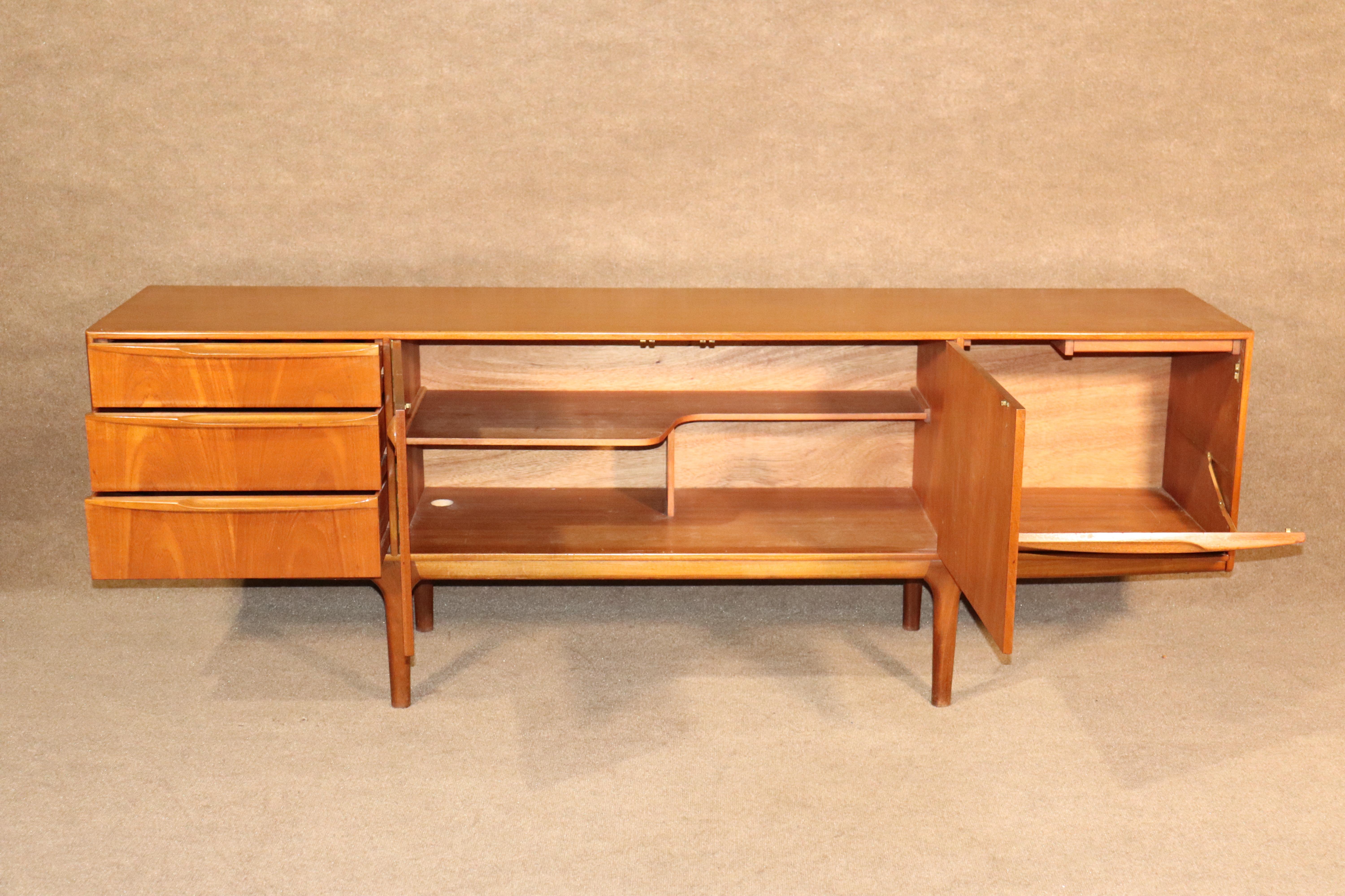Long Danish modern sideboard with sculpted accents. Handsome mid-century design with unique storage. Drawers, cabinet, and flip down bar storage. Sculpted wood handles and tapered legs finish out this beautiful credenza.
Please confirm location.