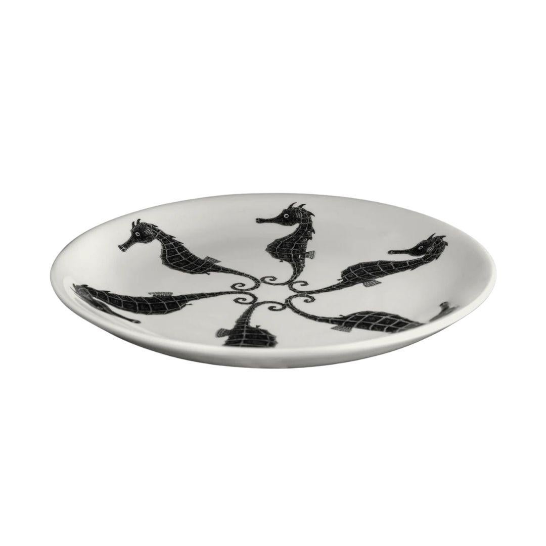 Questo piatto in ceramica fatto a mano dall'artista britannico Tom Rooth presenta una dettagliata disposizione circolare di cavallucci marini in bianco e nero, combinando l'illustrazione della storia naturale con un layout grafico e audace. Ogni