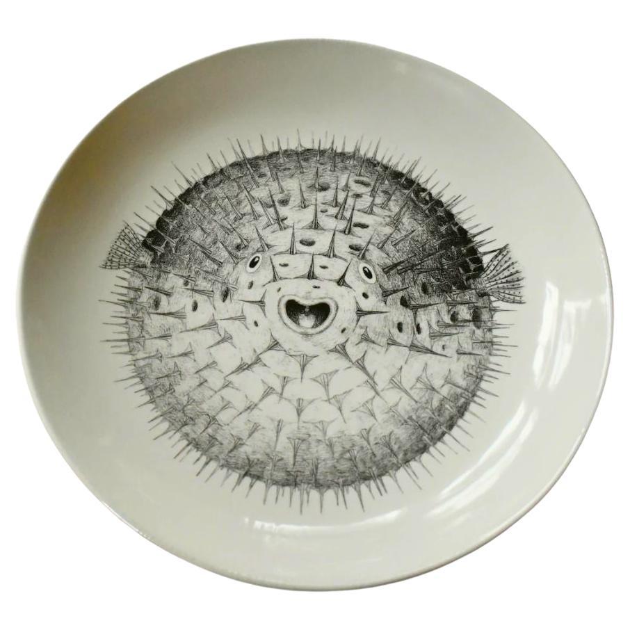 Questo piatto in ceramica fatto a mano dall'artista britannico Tom Rooth presenta un'impressionante illustrazione in bianco e nero di un pesce palla, dettagliata nel suo caratteristico stile di storia naturale. Realizzato in piccoli lotti nel Regno