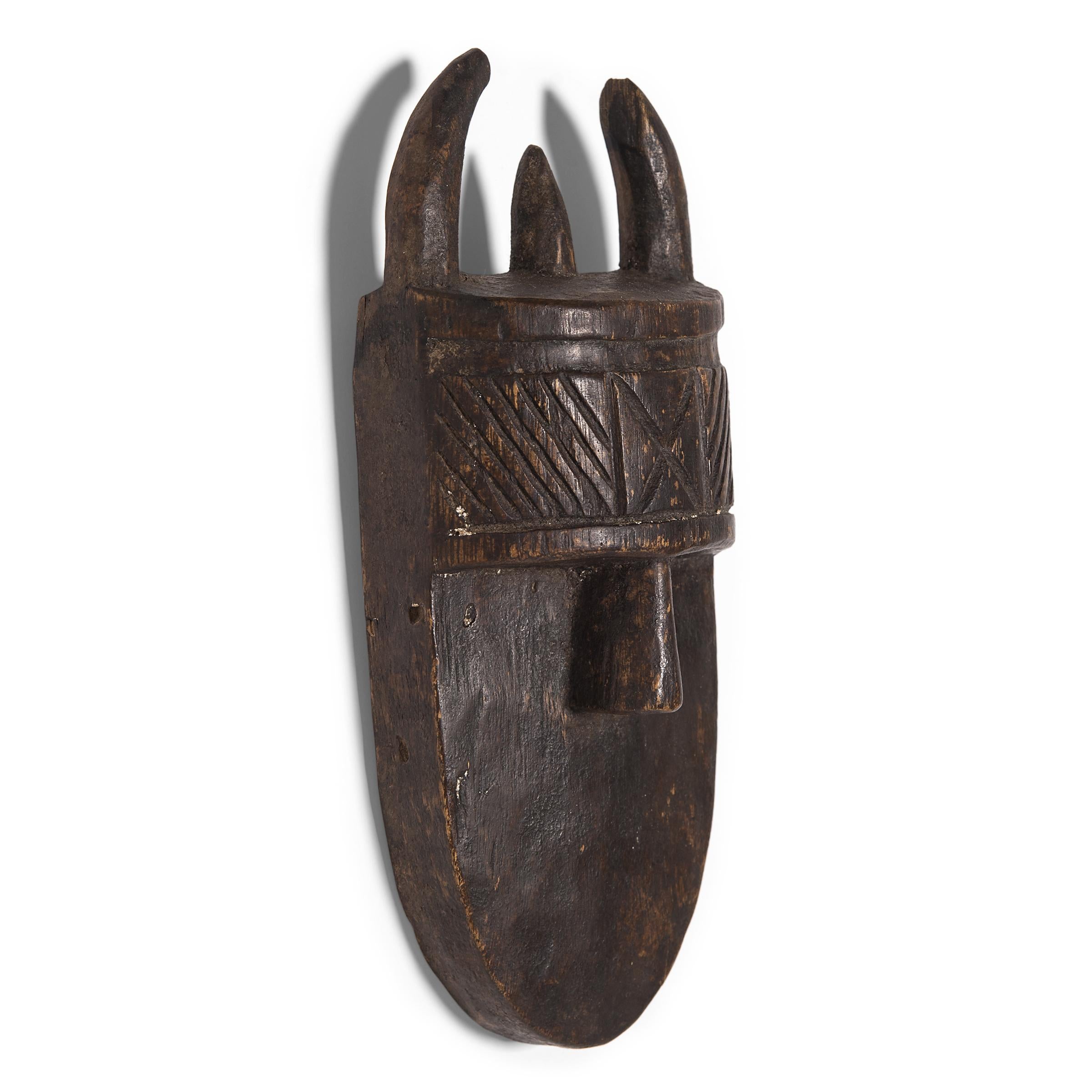 Attributed to the Toma people of present-day Guinea and Liberia, this wooden mask is carved in the style of the Angbai mask, used by the Poro initiation society to depict the forest spirit Landai. Fearsome masks that are sometimes over five feet