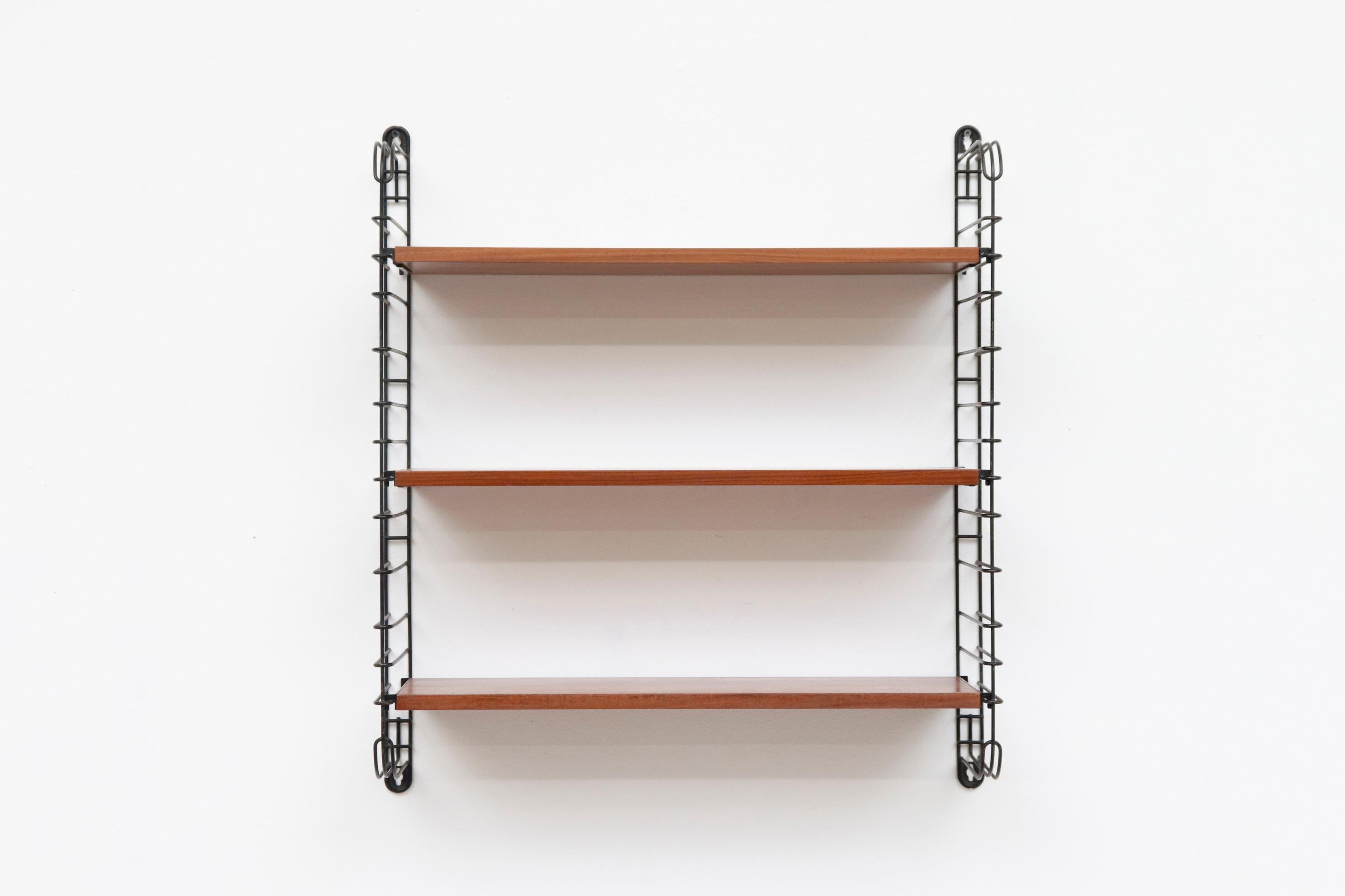 Tomado industrial wall mounted shelves with black enameled metal risers and 3 teak shelves. Lightly refinished with wear consistent with age and use. Interchangeable and expandable. Other shelves also available (LU922423517502,) listed separately.