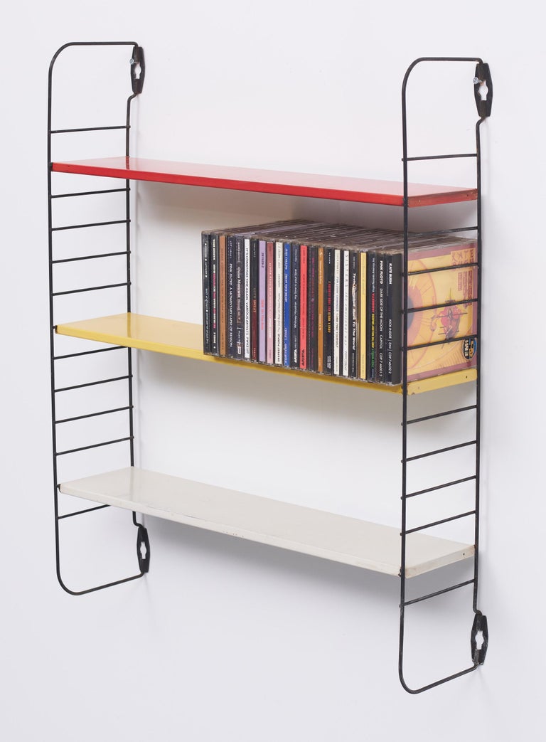Dutch metal wall rack. Three metal shelves. In primary colors. Red yellow 
and Grey. This is the pocket range. The size is perfect for the pocket books 
from the 50s and 60s. signed.