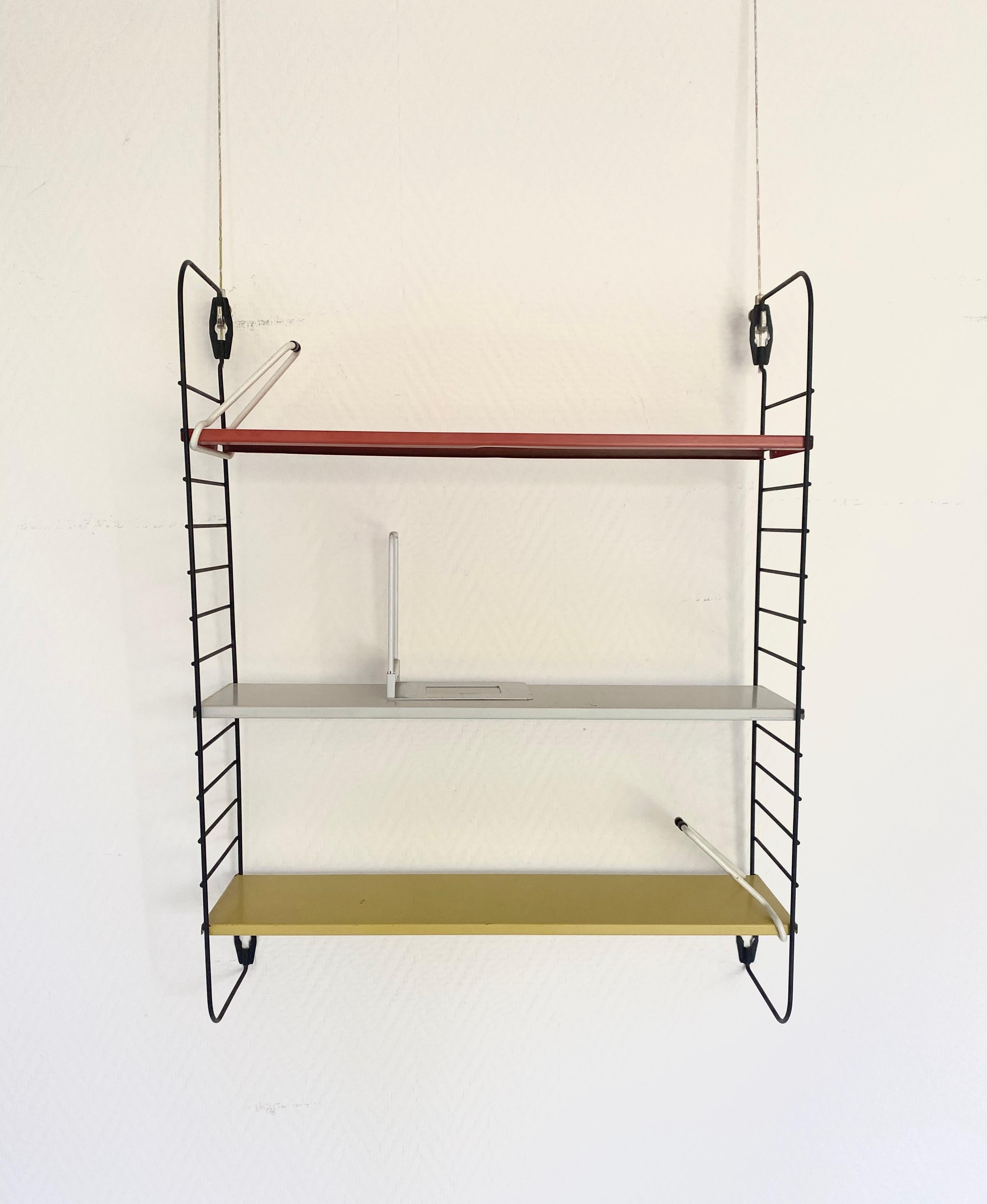 This modular industrial piece, features 3 shelves, two gliding stands for books and one stand to place upon the shelves. These stands are not often to be found anymore.
Every shelf was imprinted ‘Tomado made in Holland’ and this system looks as it