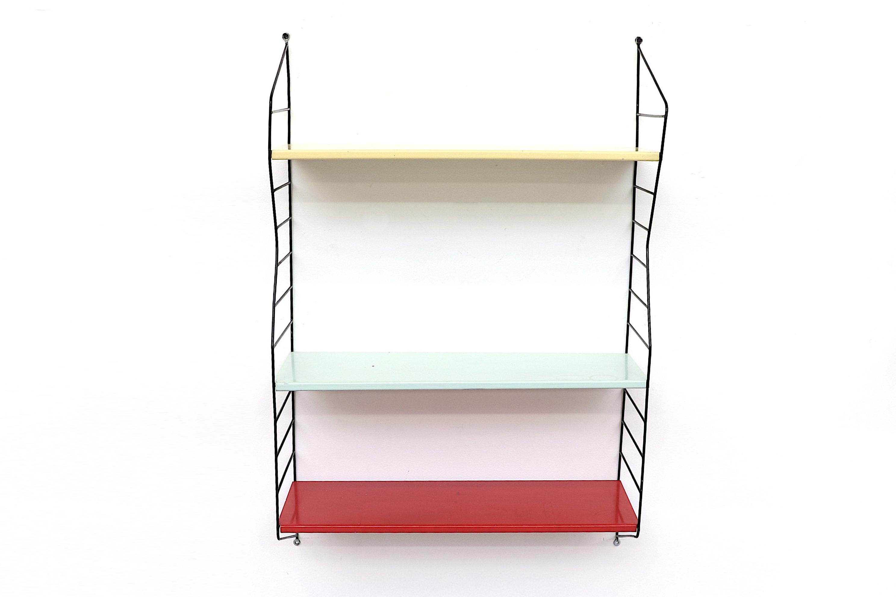 Tomado style wall mount book shelf with three enameled metal shelves in yellow, mint and red with zig zag Industrial black enameled metal sides. In original condition with visible wear and enamel loss. Can ship flat.