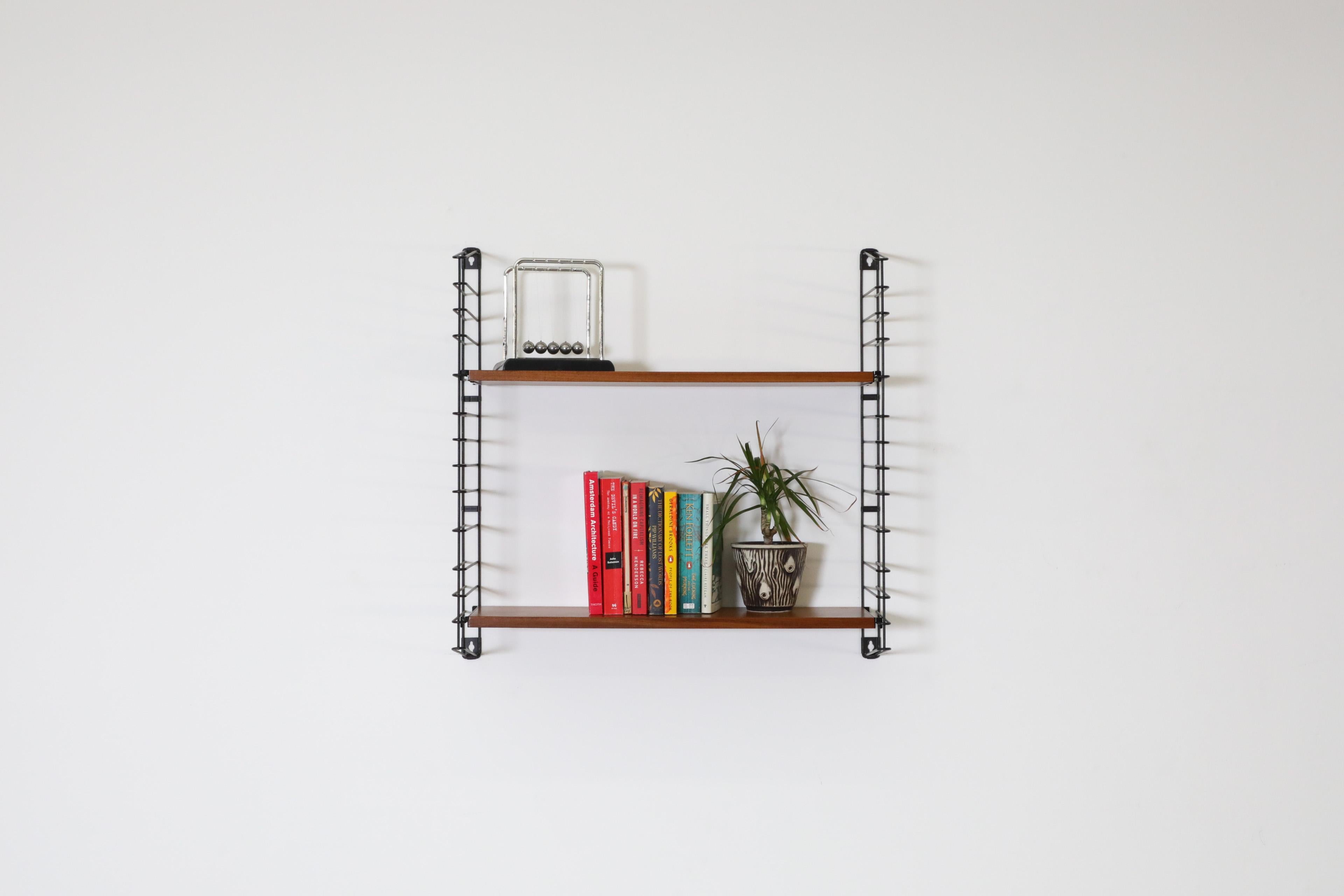 Dutch Mid-Century, single section, TOMADO shelving unit with adjustable teak shelves and black enameled metal risers. Functional and attractive wall mount shelves perfect for displaying books, plants and other accessories. In original condition with
