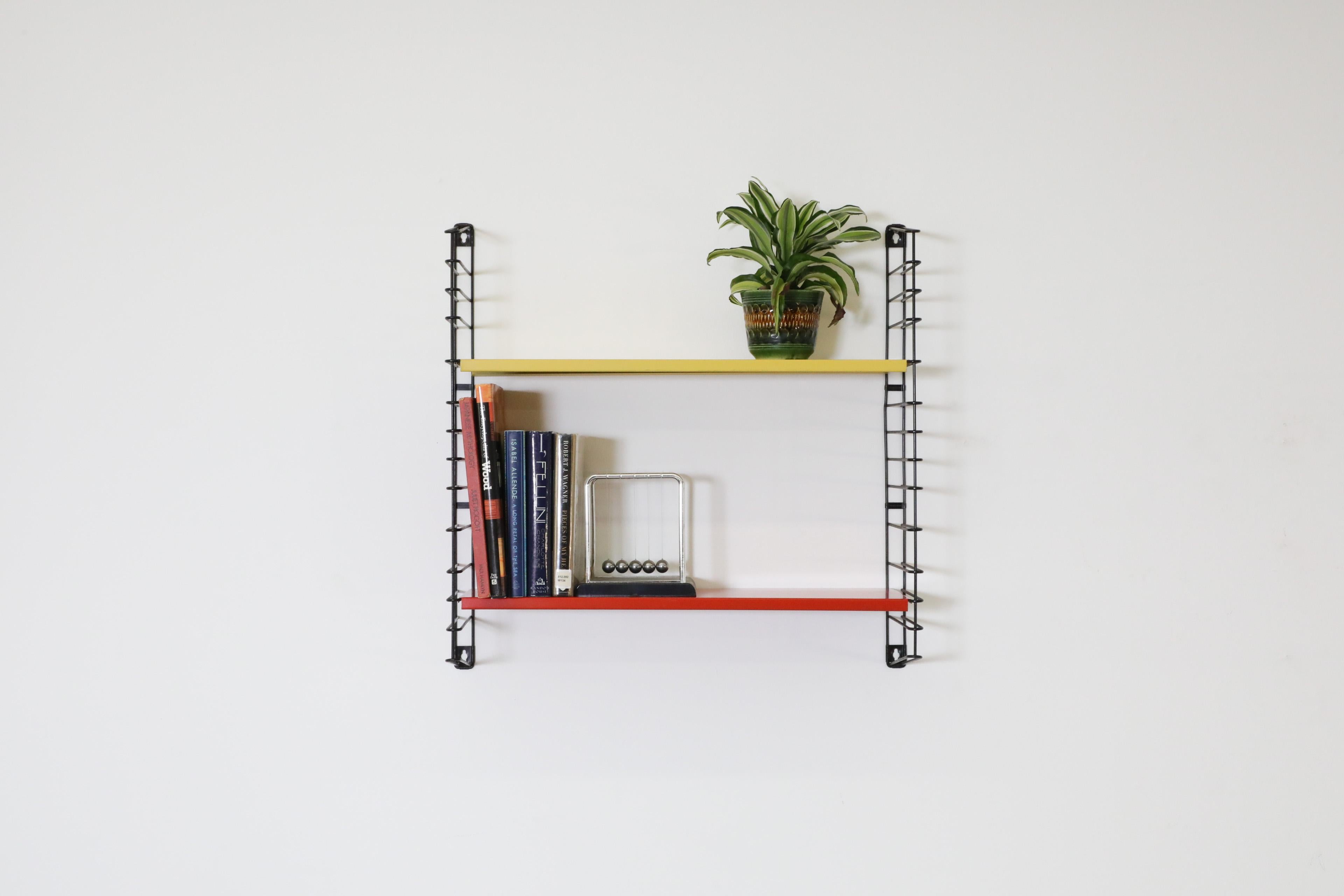 Dutch Mid-Century single section industrial style wall mounted shelving by the iconic Tomado company. Features Yellow and red enameled metal shelves on black wire risers with some visible wear consistent with age and use. Perfect for books or