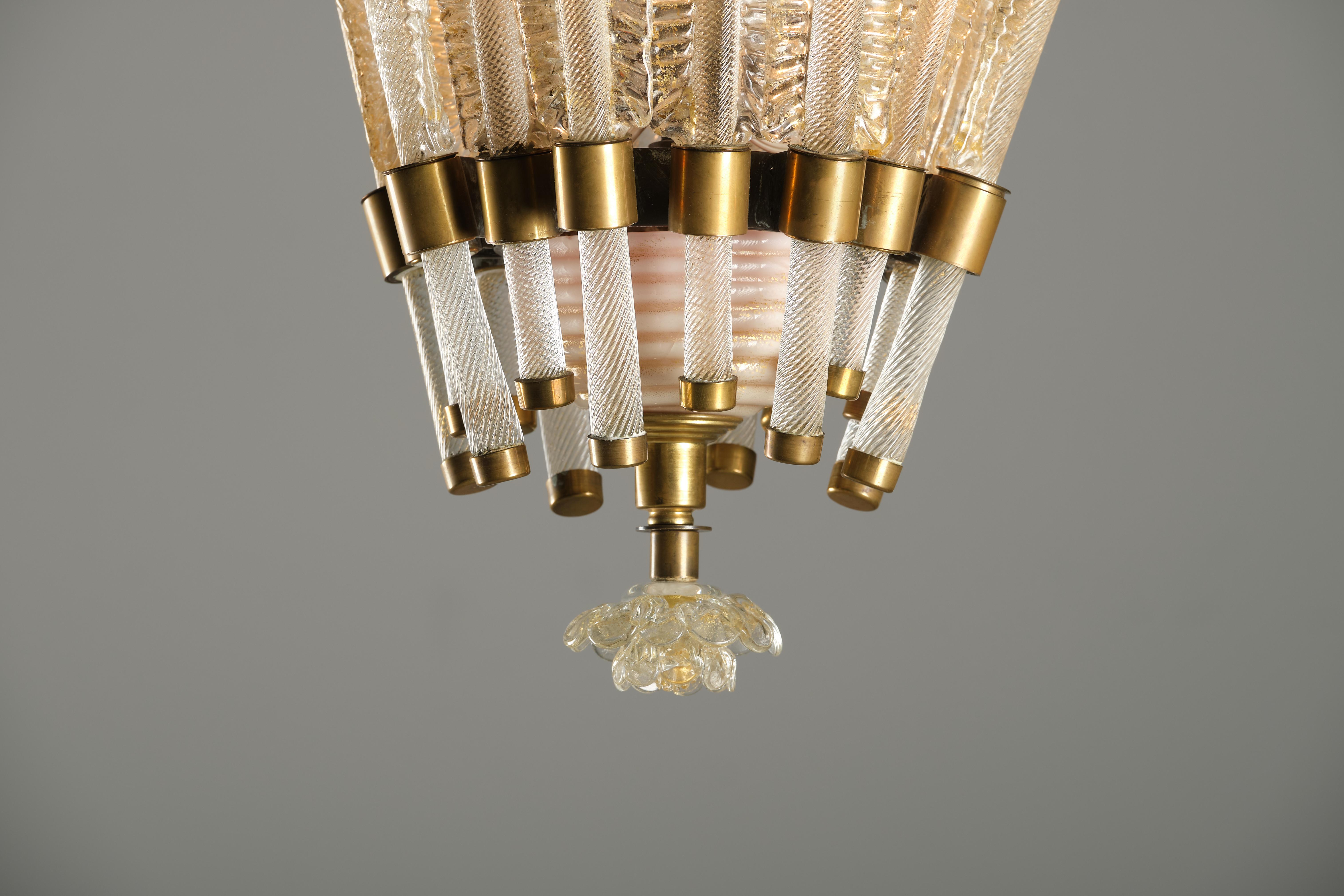 This beautiful chandelier was designed by Tomaso Buzzi for Venini in the 30s. The brass structure supports the decorative elements in transparent Murano glass and gold leaf, which alternate in two different sizes along the circular perimeter. A