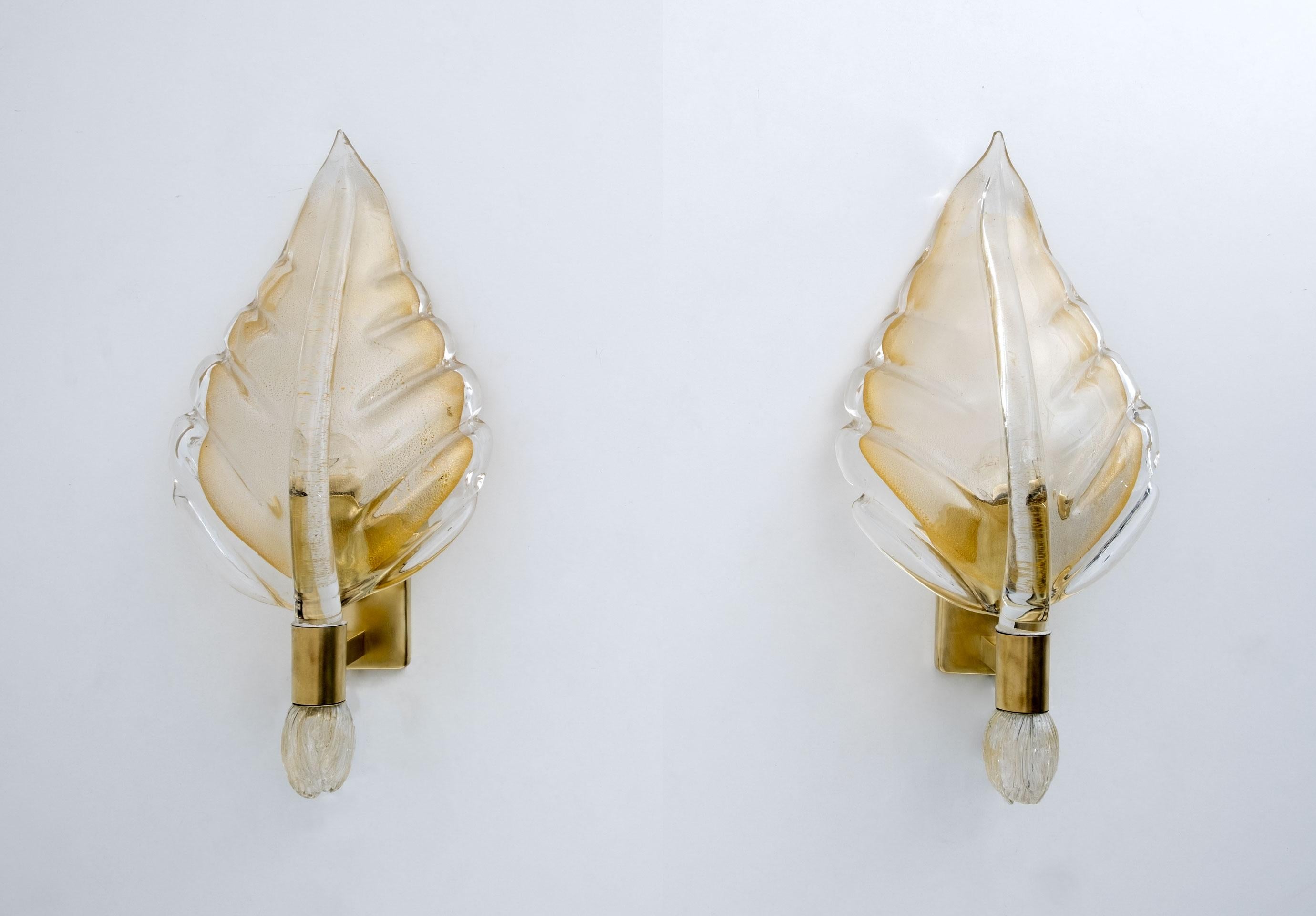 Pair of leaf-shaped appliques in Murano glass attributed to Tomaso Buzzi for Venini Italia, 1950. Pulegoso glass and filigree glass with gold dust, mounted on a brass structure. Produced by Venini & C., Murano, Italy in 1950.
We polished the brass.