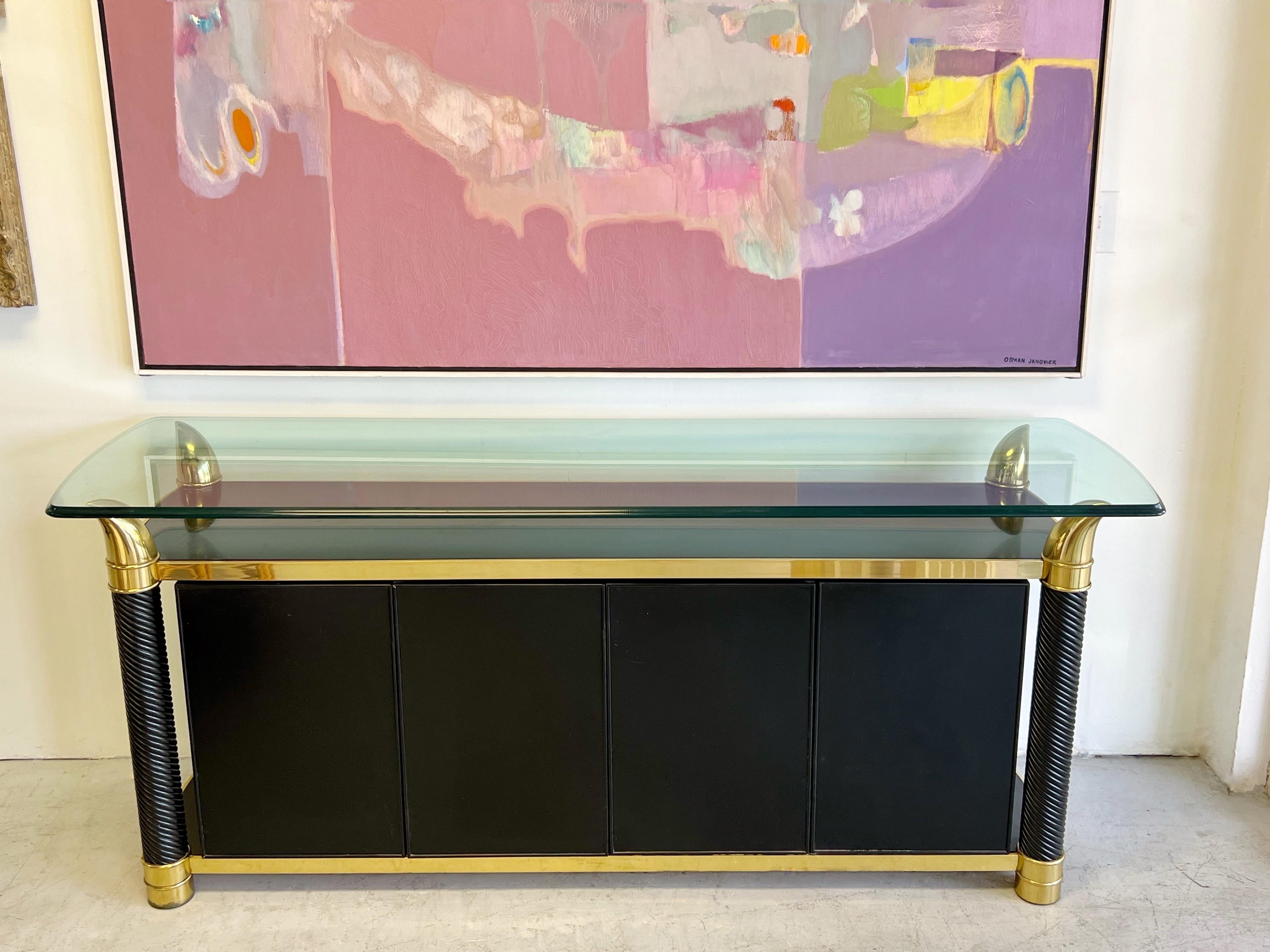 Brass and lacquer sideboard with suspended glass top by Tommaso Barbi. One of his most iconic designs. 
The side doors when opened reveal adjustable shelves, the 2 center doors hide a long drawer and a long adjustable shelf.