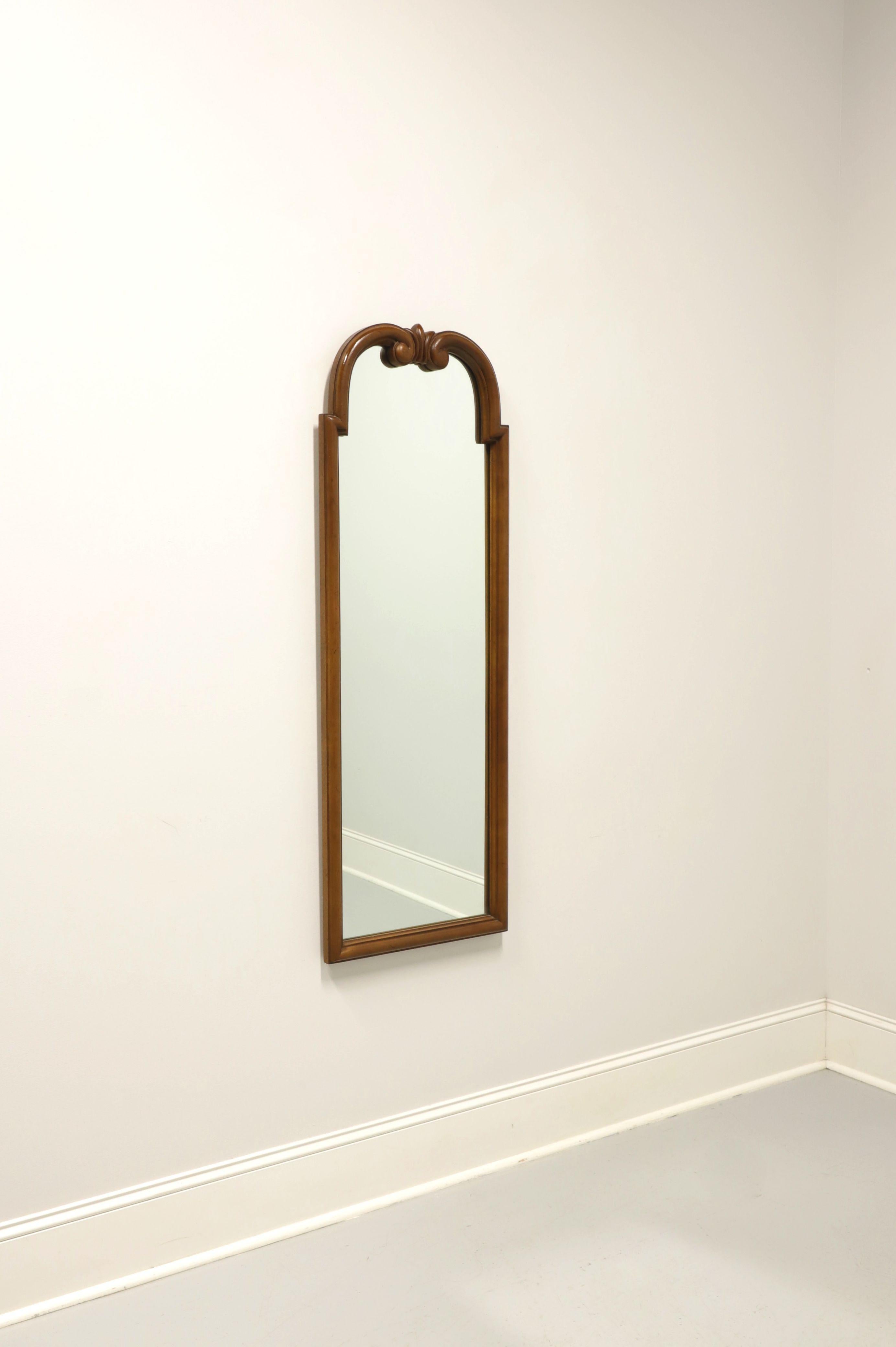 A Regency style wall mirror by Tomlinson Furniture. Mirrored glass in a walnut wood frame. Features arched top with a decorative fleur-de-lis to center top. Made in North Carolina, USA, in the mid 20th century.

Measures: 18.5 W 2 D 52.75 H,