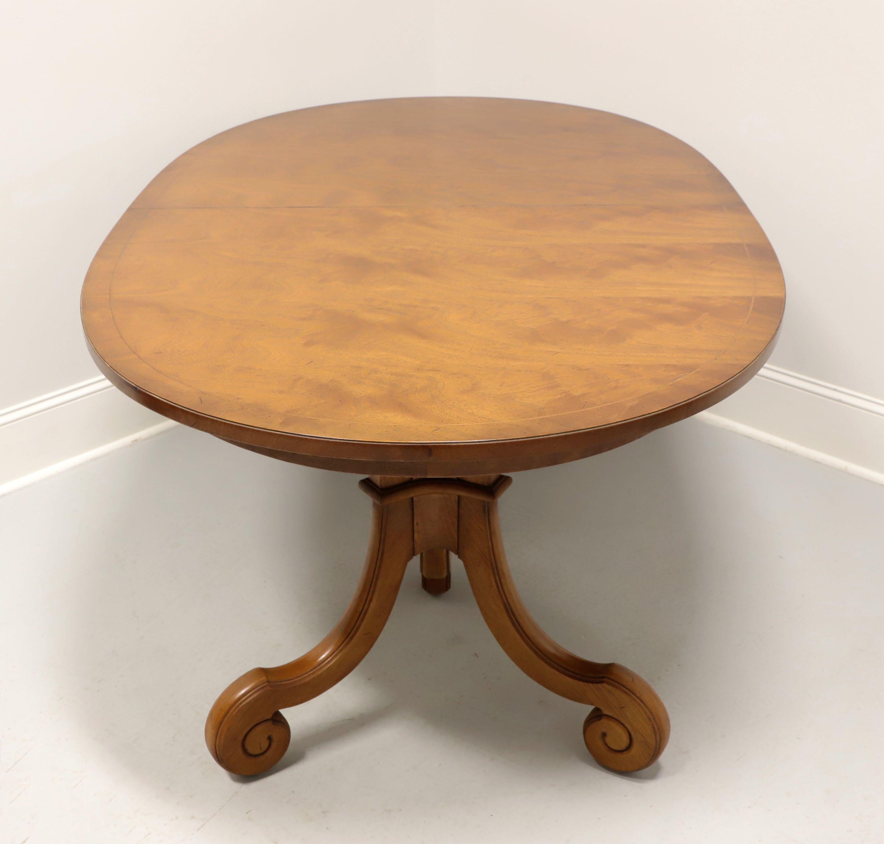 A Neoclassical style oval dining table by Tomlinson Furniture. Mahogany with their lighter color Tokay finish, banded top and double pedestals with three scroll-like legs. Expandable on wood expansion sliders, but no extension leaves are present.
