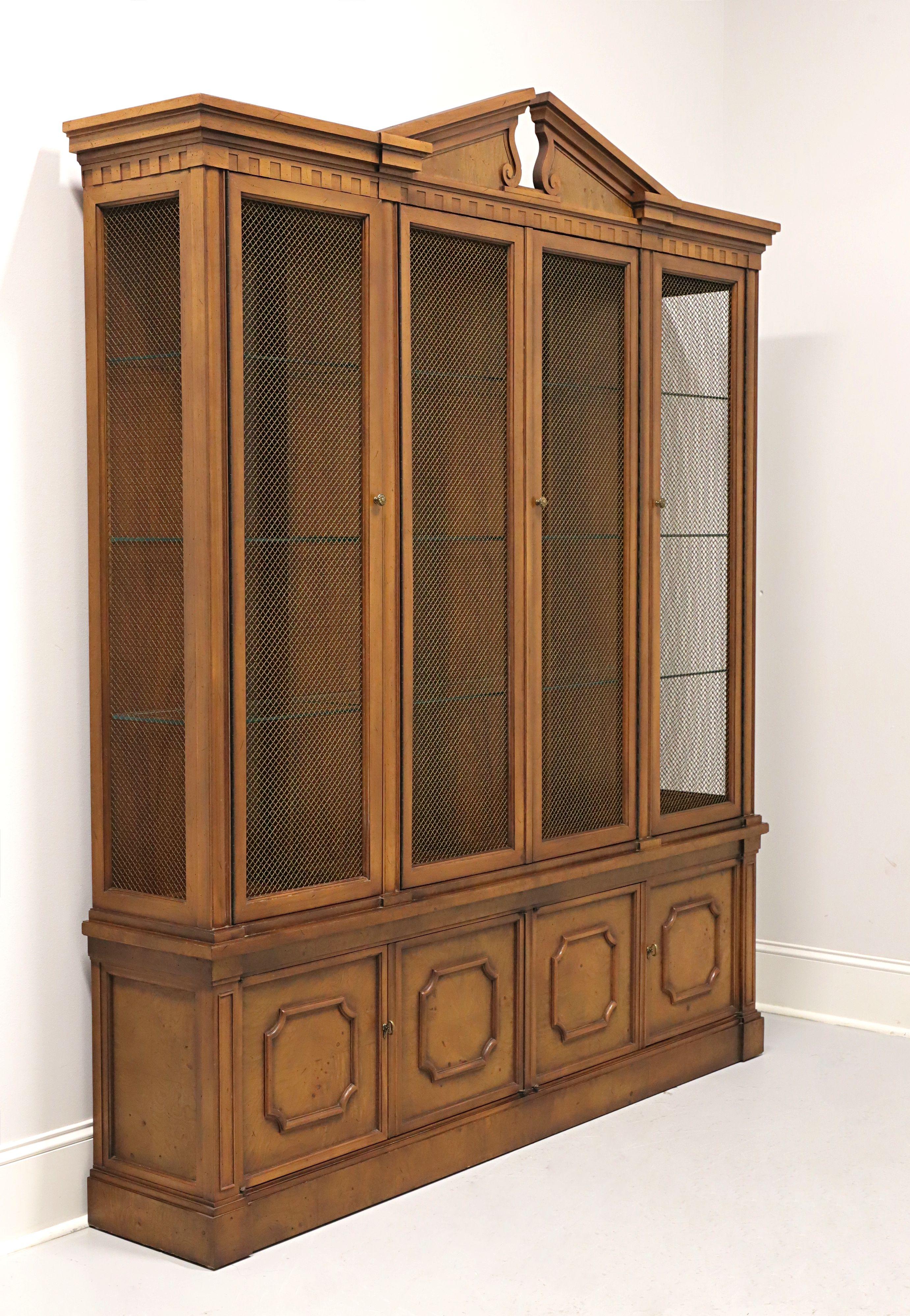 A china display cabinet in the neoclassical style by Tomlinson Furniture. Walnut with their slightly distressed antique Nutmeg finish, narrow profile design, brass hardware, pediment to top, brass wire mesh door & side panels, and raised panel lower
