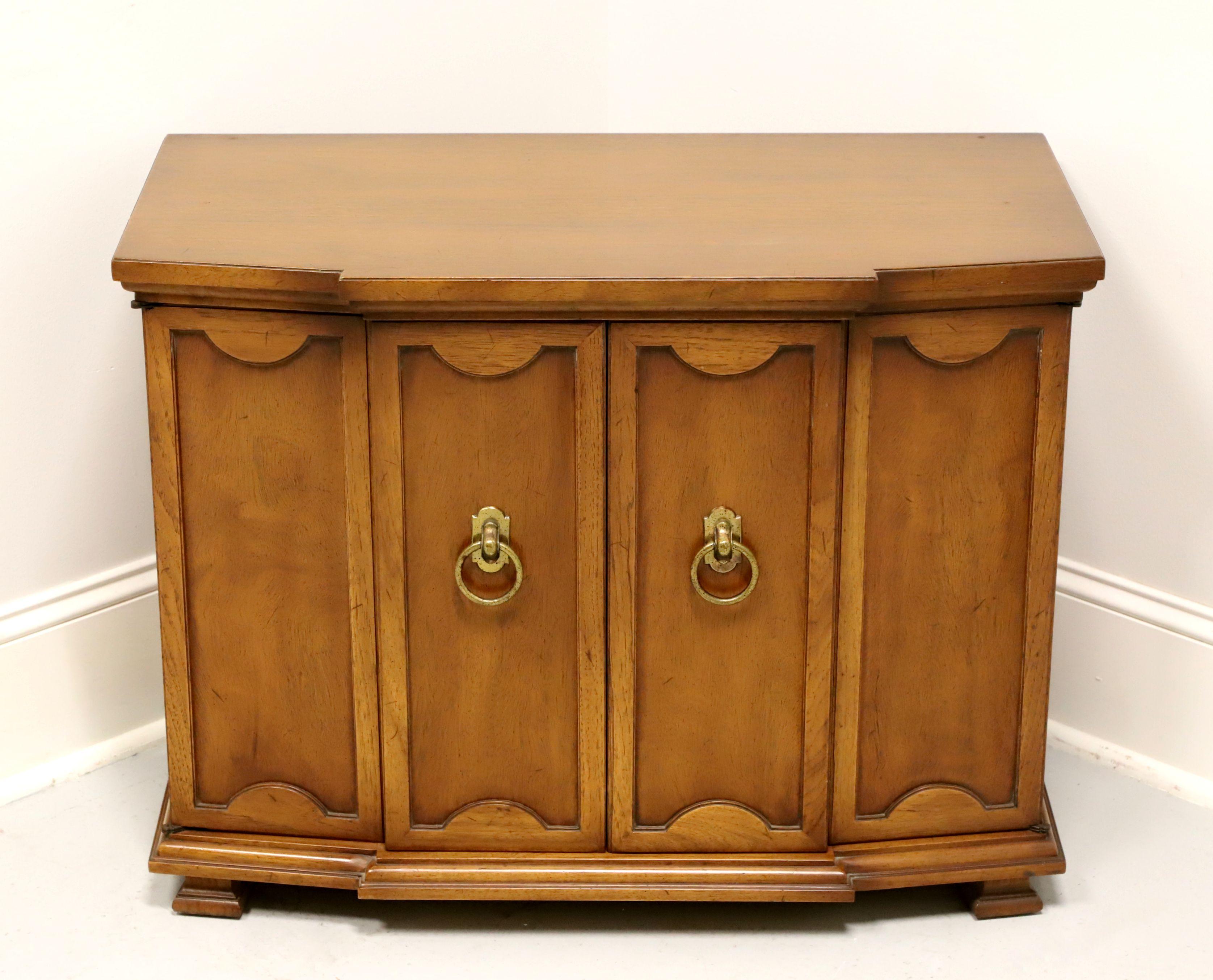 A Neoclassical style console cabinet by Tomlinson Furniture. Walnut with their Tokay finish, slight distressing and brass hardware. Features cabinet with two bi-fold doors revealing a storage area with one adjustable wood shelf. Made in North