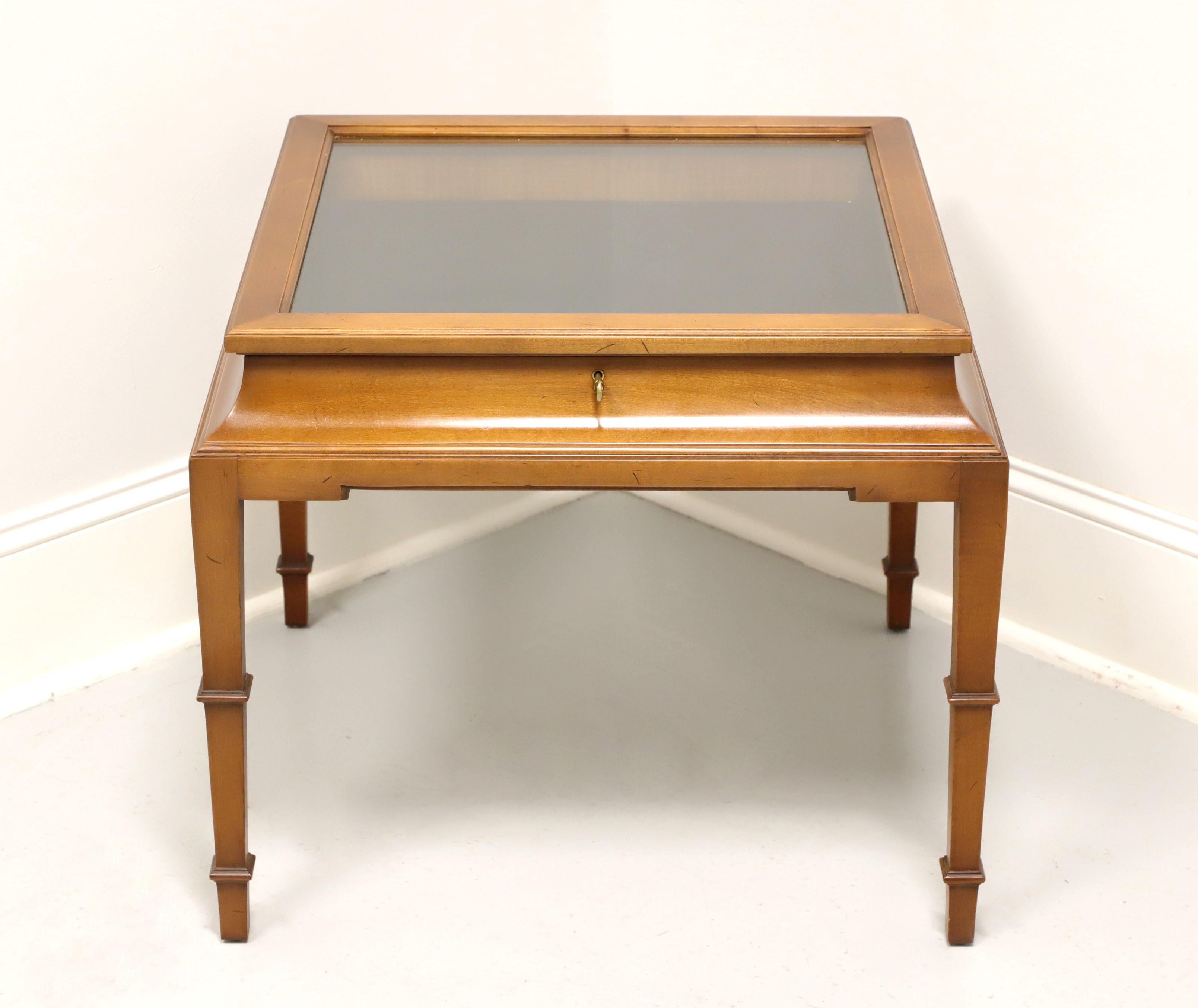 A French Louis XVI style square glass top accent table with display case by Tomlinson. Nutwood with a slightly distressed finish, framed glass top, black felt lined interior, tapered legs and spade feet. Features a lockable framed glass lift top
