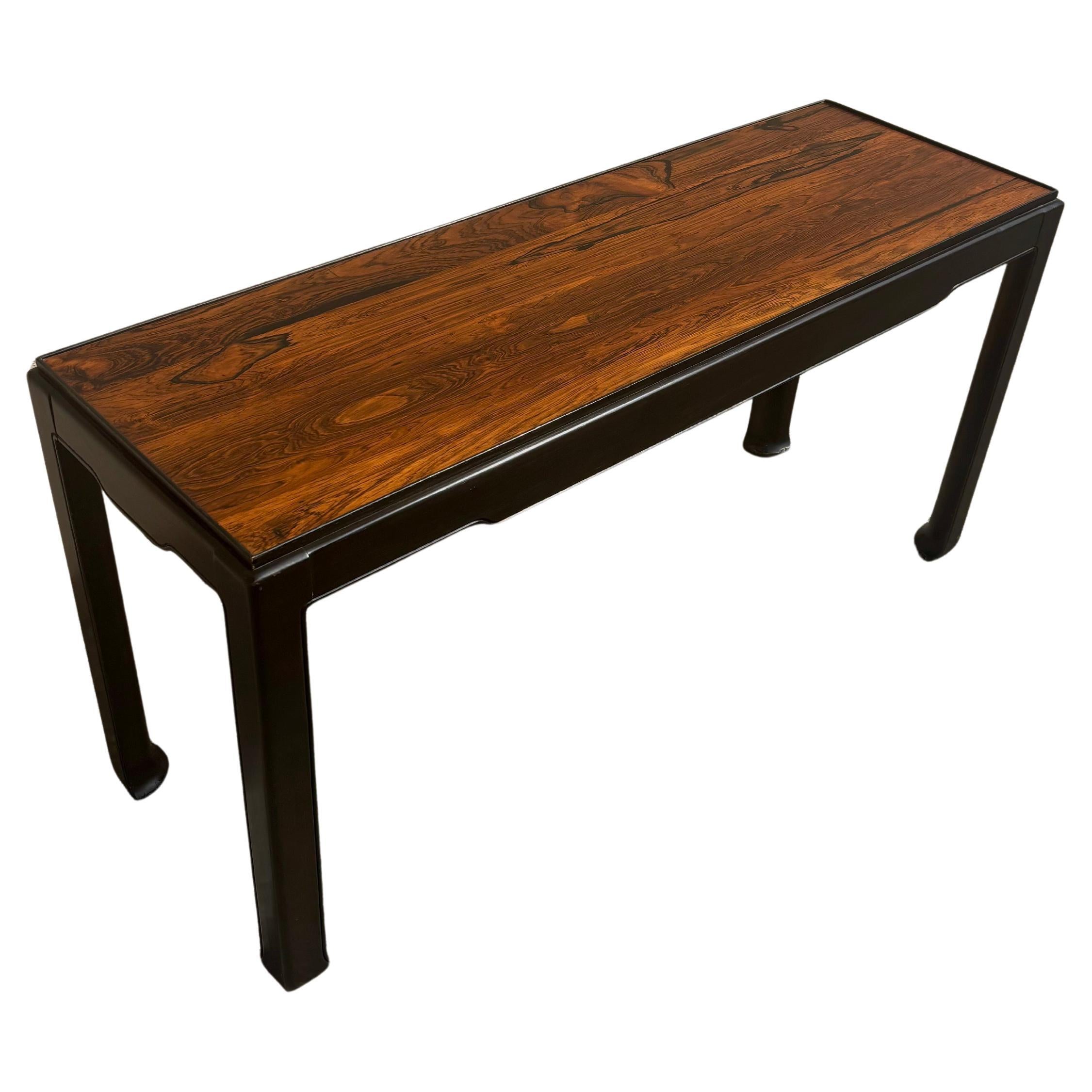 A beautiful Ming style console table made by Tomlinson. Made in the mid 20th century. Supporting a rosewood top. 

Classic elegant silhouette with a touch of flair at the top and at the feet. Sides have a very dark brown lacquer that appears almost