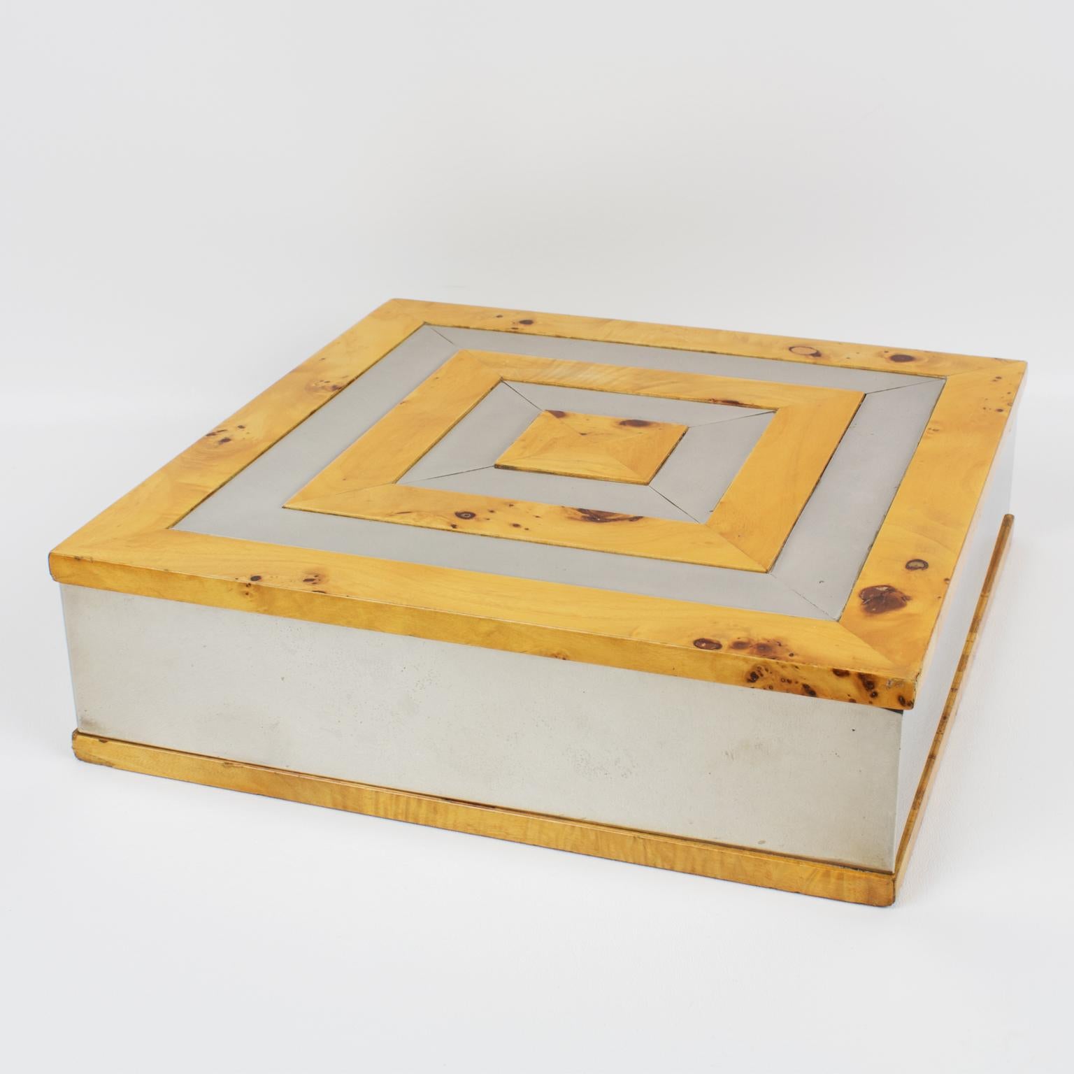 Tommaso Barbi ha diseñado esta original caja decorativa. La pieza se fabricó en Italia hacia el año 1960. Su forma modernista es cuadrada y sustancial, con metal cromado y marquetería geométrica de madera burlada en la tapa. El interior también es