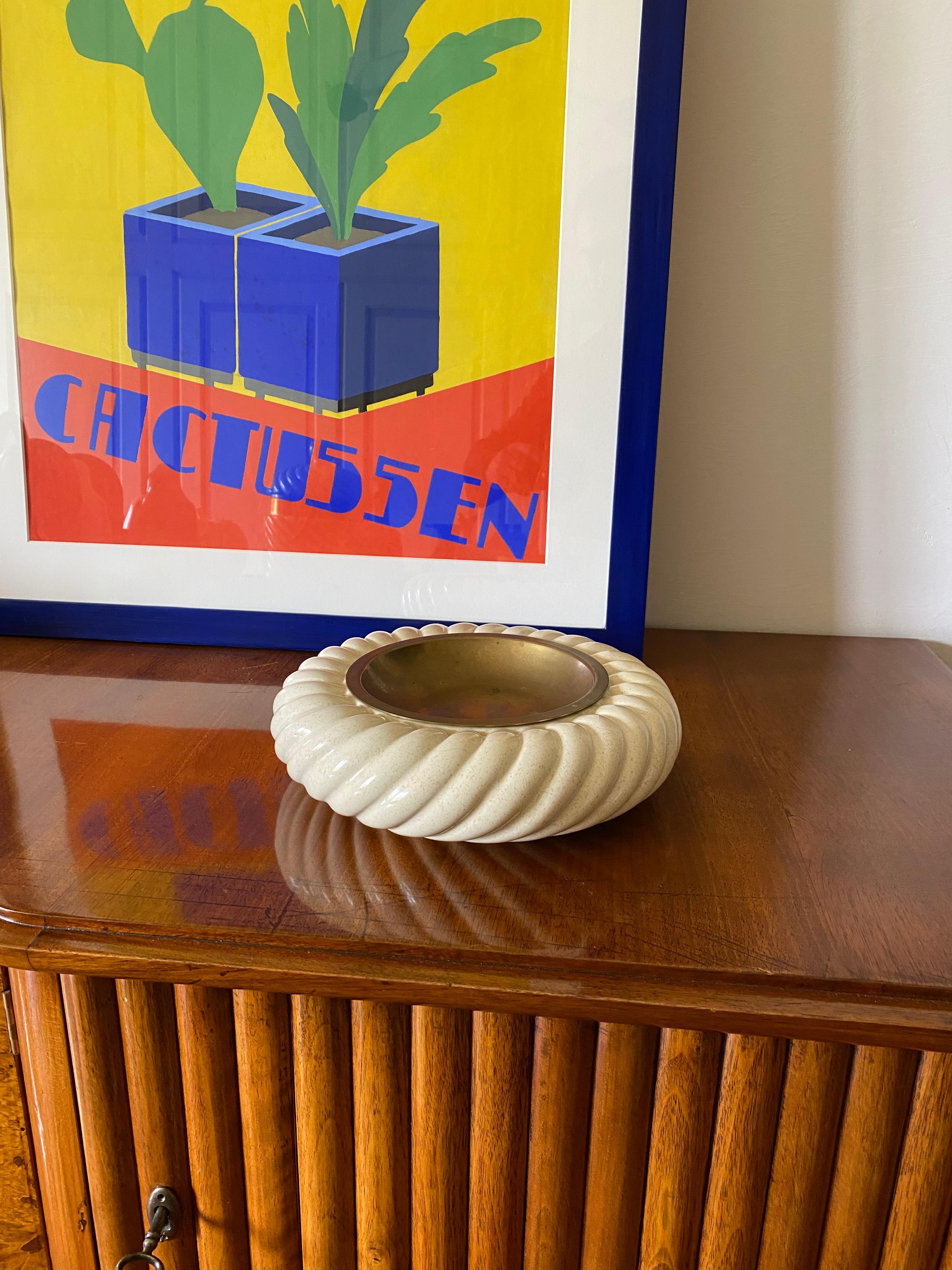 Cremefarbener Keramik-Aschenbecher / vide poche entworfen von Tommaso Barbi

hergestellt von B Ceramiche, Italien 1970 ca.

Messing, Keramik

25 x 25 x 7 cm

Signiert und markiert auf der Unterseite

Condit: gut im Einklang mit Alter und Gebrauch,