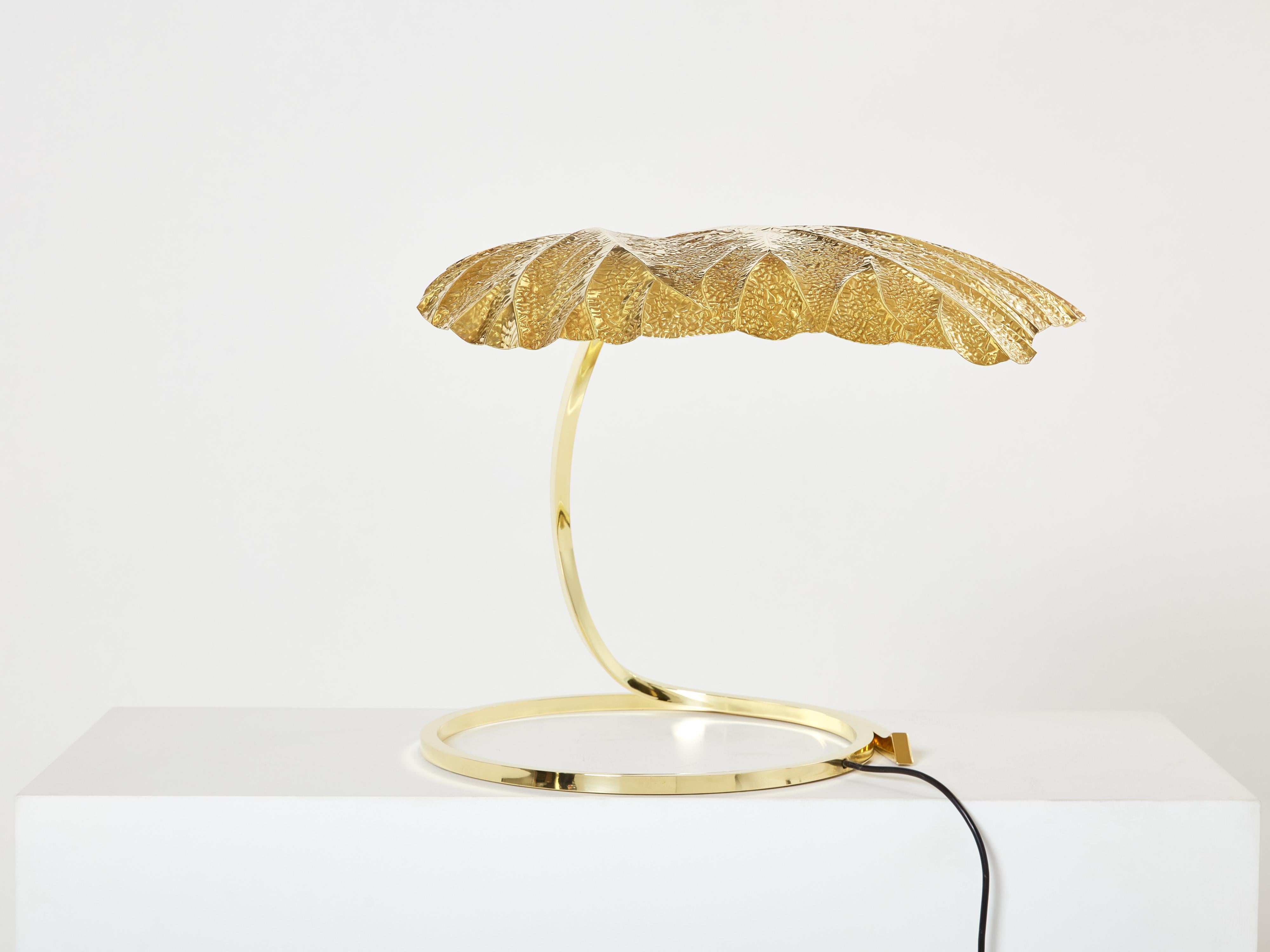 This iconic single leaf Rhubarb table lamp was designed by Tommaso Barbi and Carlo Giorgi was produced by Bottega Gadda in Italy in the 1970s. The circular brass frame sweeps upwards from the base to support the large, decorative, hammered brass