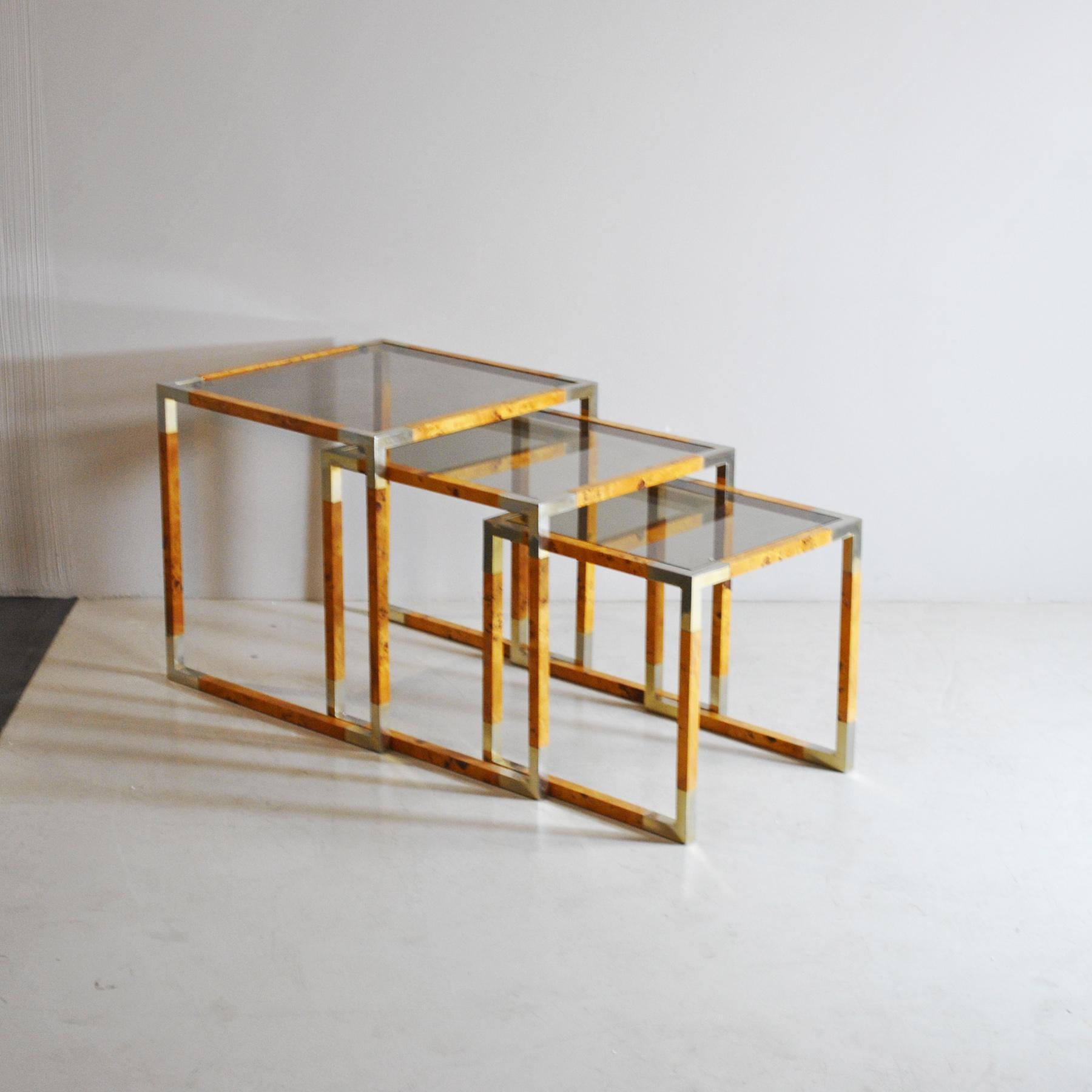 Trio of so-called nesting tables in the Tommaso Barbi style. Briar-root veneered wood structure, angles in metal and smoked glass, production from the late 1960s.

Medium size 42 x 42 x 42 cm
Small size 37 x 37 x 37 cm.