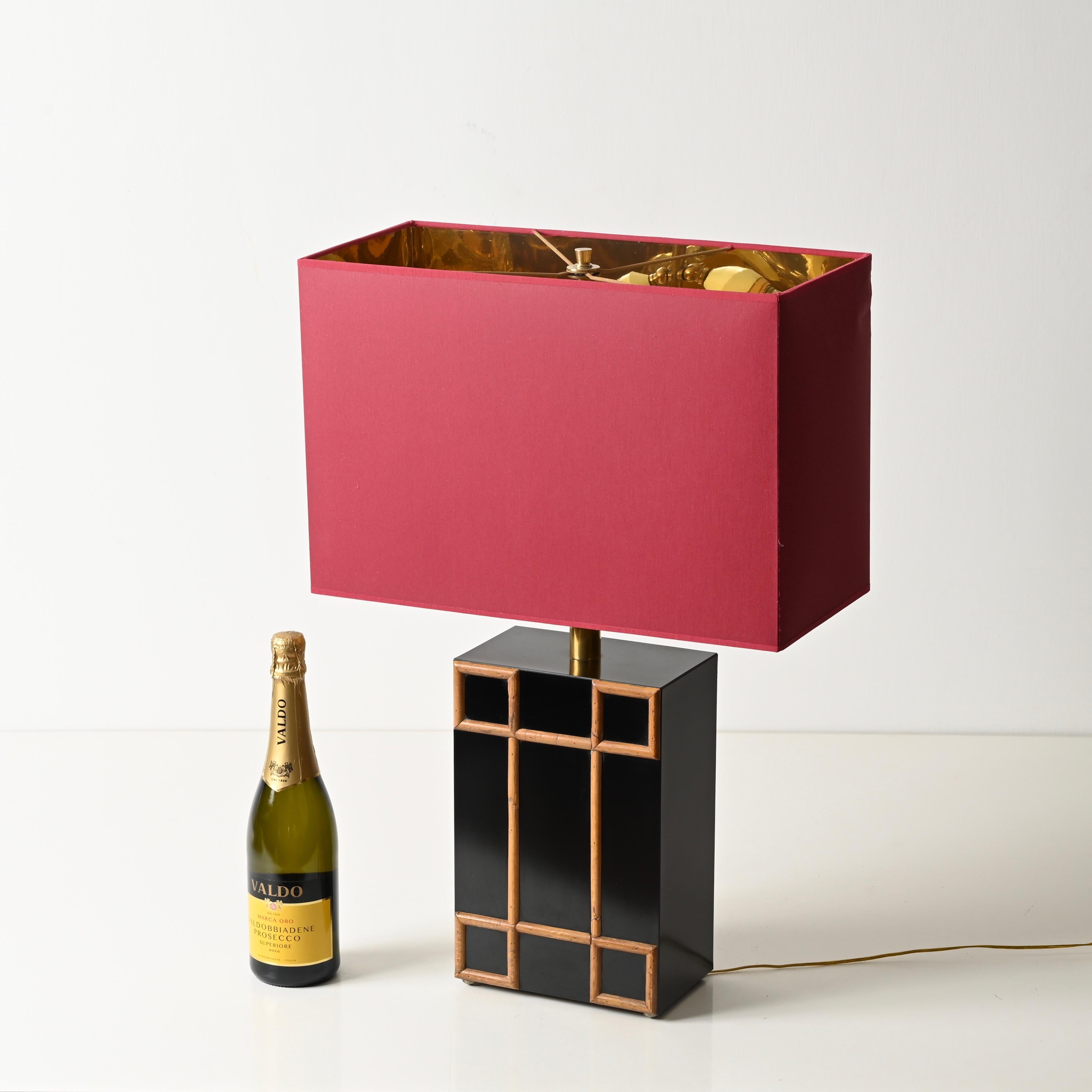 Stunning Mid-Century table lamp made of black laminated wood and brass, featuring decorative bamboo inserts and completed by a burgundy lampshade. This incredibly elegant and unique organic lamp was designed by Tommaso Barbi and produced in Italy
