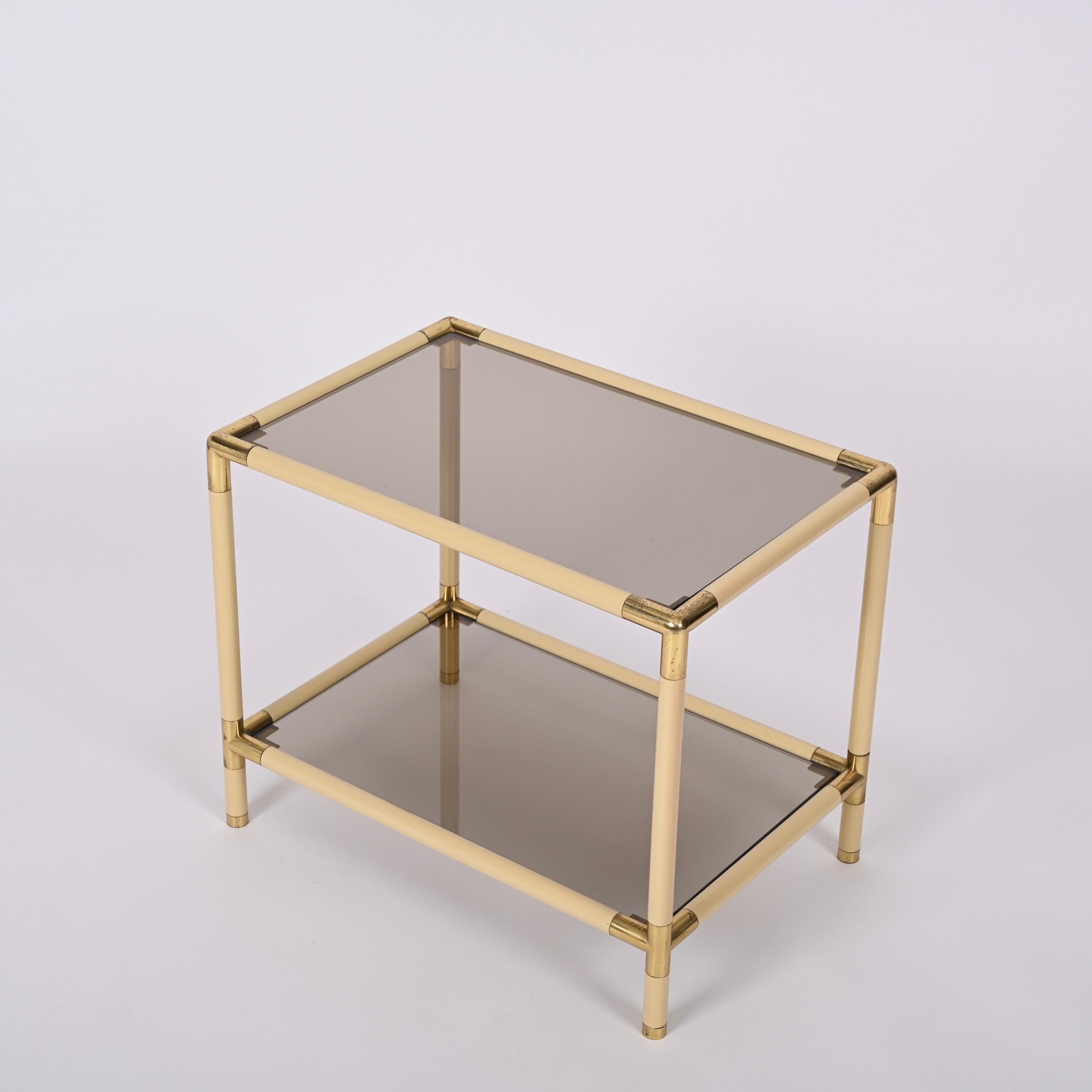 Gorgeous midcentury rectangular cocktail table in enameled metal and brass with smoked glasses. This wonderful object was designed by Tommaso Barbi in Italy in the 1970s.

This stunning coffee table features a tubular enameled metal structure in a