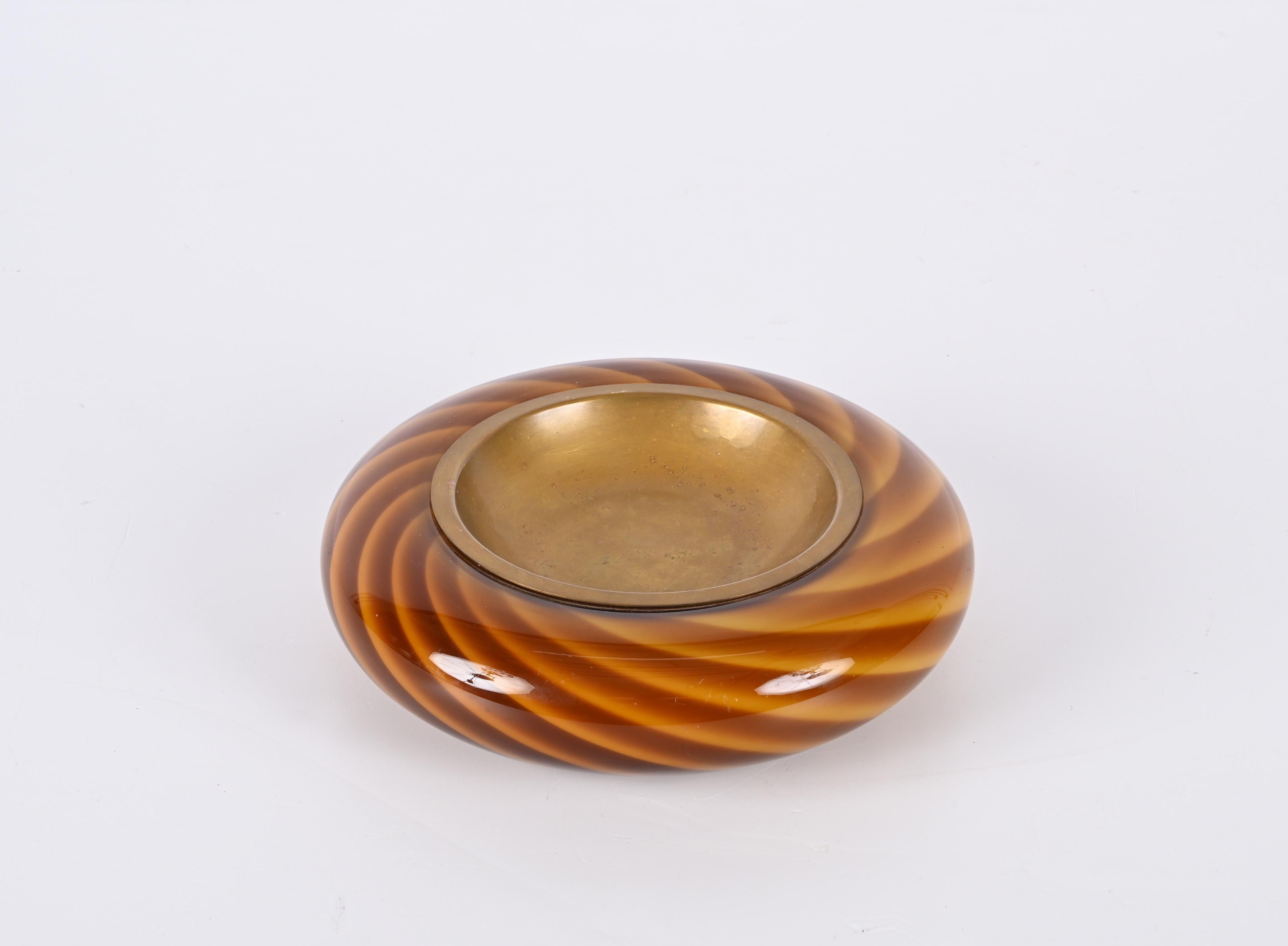 Incredible Midcentury Murano Glass and Brass Circular Italian Ashtray, 1970s. Tommaso Barbi produced this incredible piece during the late 1960s in Italy.

The combination of wonderful Murano glass colours, red and yellow, with a brass plate on top.